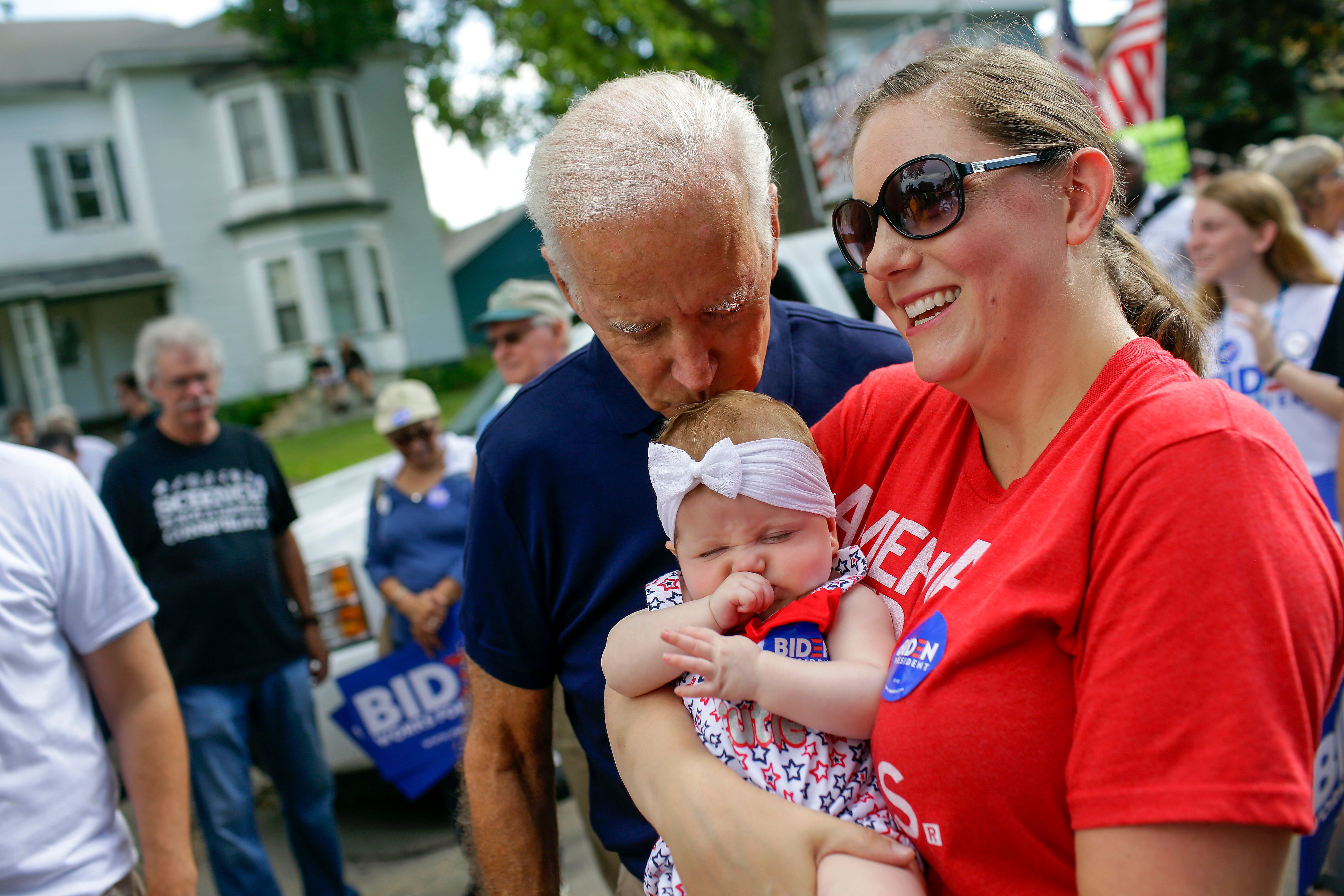 Democratic presidential candidate, former Vice President Joe Biden kisses Ashley Blasberg on her head as her mother Erin Blasberg looks on during the Fourth of July parade on July 4, 2019 in Independence, Iowa. (Photo by Joshua Lott/Getty Images)