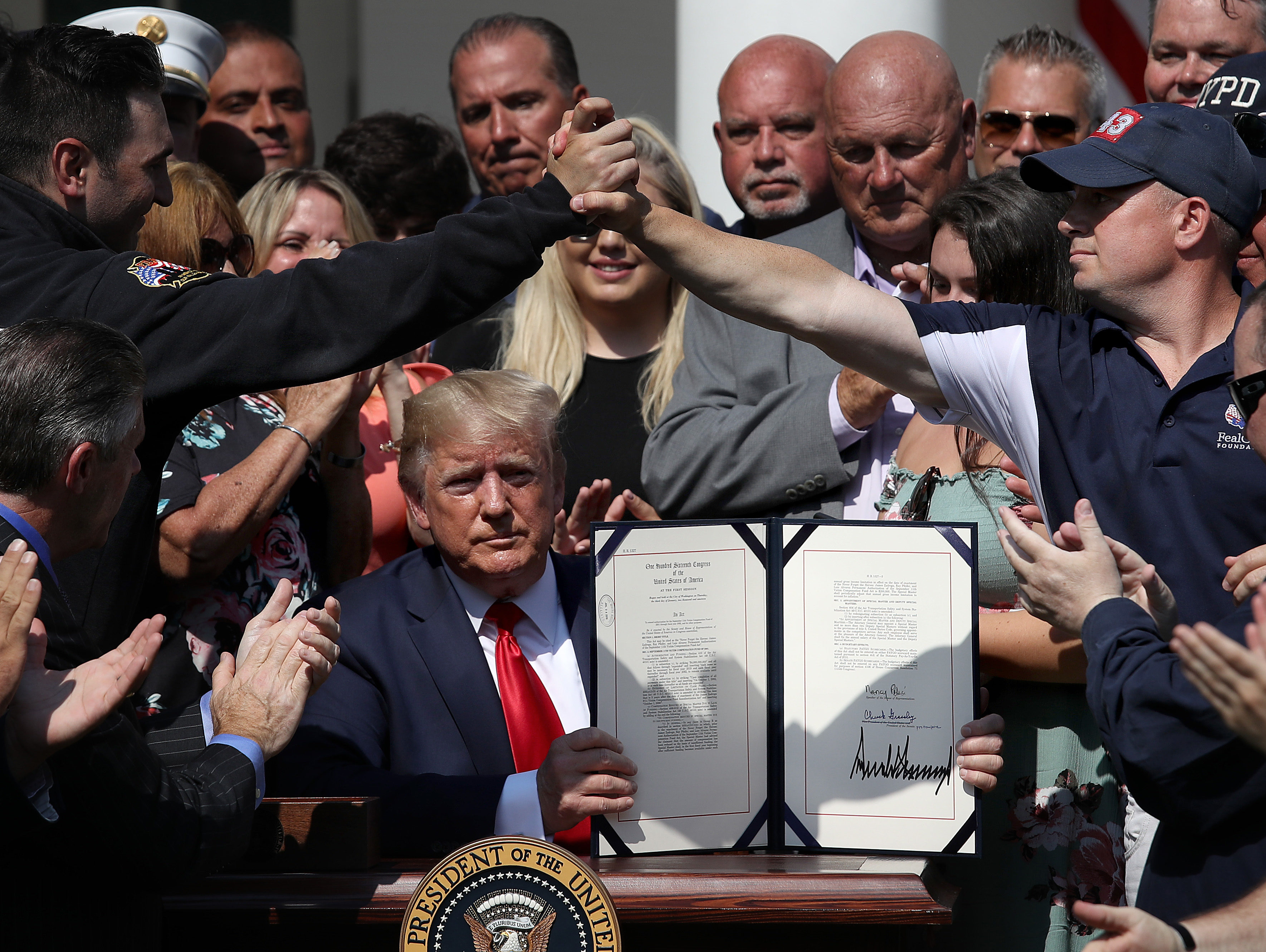 WASHINGTON, DC - JULY 29: As first responders and their families celebrate, U.S. President Donald Trump shows off his signature on H.R. 1327, an act to permanently authorize the September 11th victim compensation fund, in the Rose Garden of the White House July 29, 2019 in Washington, DC. The bill will provide continued funding for health care compensation for first responders of the 9/11 attacks at the World Trade Center. (Photo by Win McNamee/Getty Images)