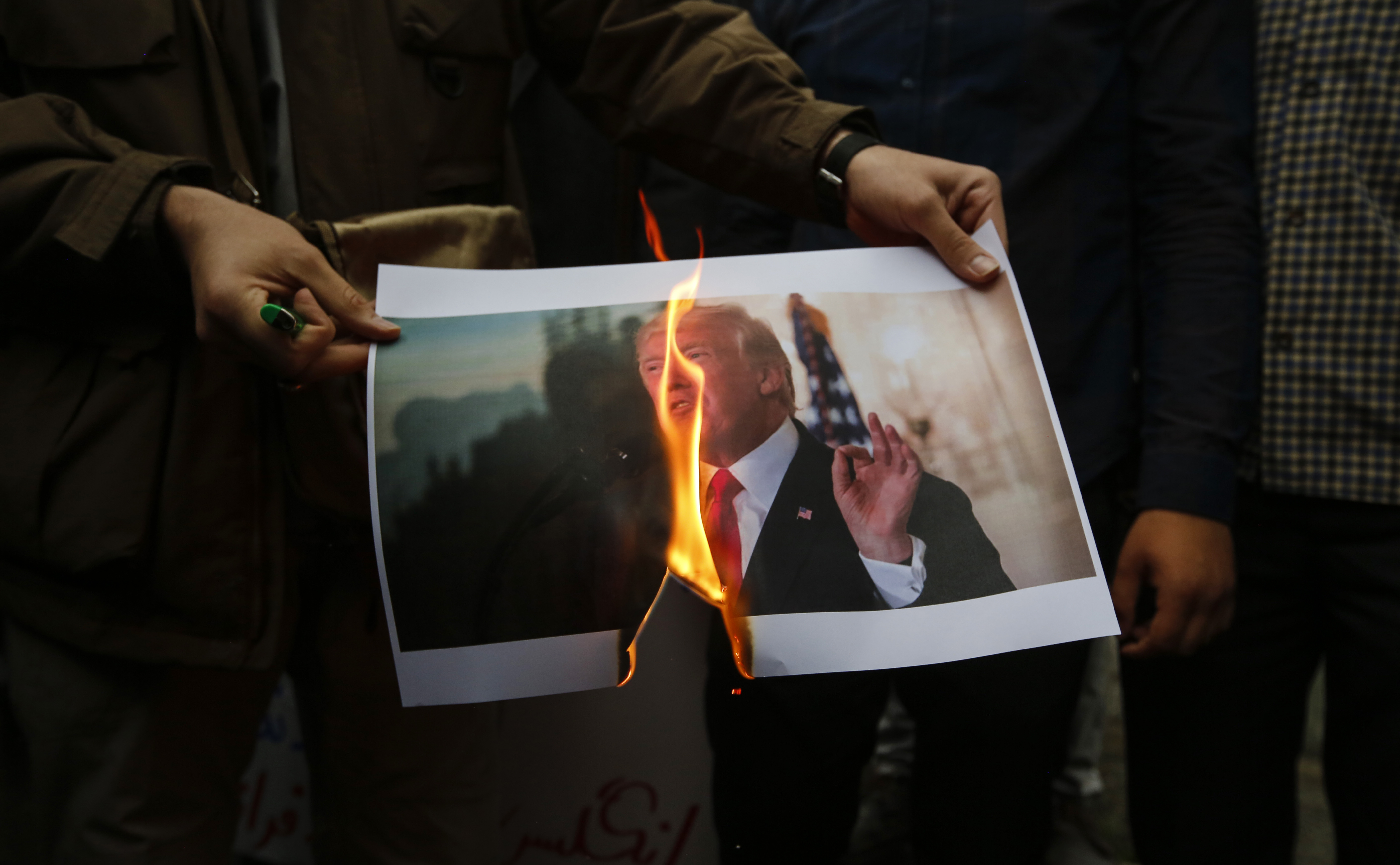 Iranians burn an image of US President Donald Trump during an anti-US demonstration outside the former US embassy headquarters in the capital Tehran on May 9, 2018. - Iranians reacted with a mix of sadness, resignation and defiance on May 9 to US President Donald Trump's withdrawal from the nuclear deal, with sharp divisions among officials on how best to respond. For many, Trump's decision on Tuesday to pull out of the landmark nuclear deal marked the final death knell for the hope created when it was signed in 2015 that Iran might finally escape decades of isolation and US hostility. (Photo by ATTA KENARE/AFP/Getty Images)