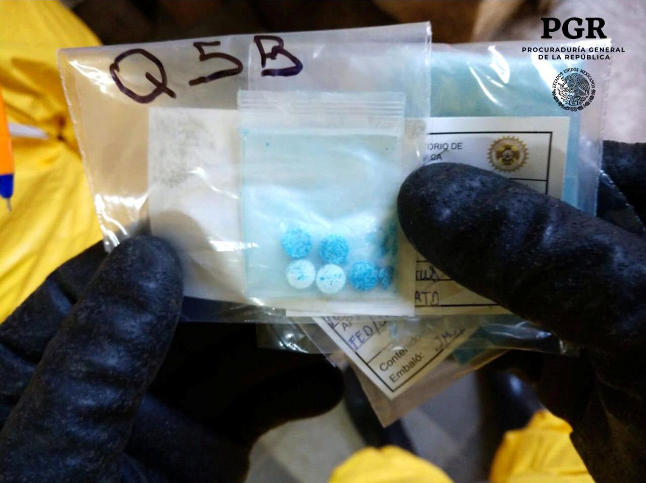 A chemical specialist in a protective suit shows pills seized at a clandestine drug processing laboratory of fentanyl located in the Azcapotzalco municipality, in Mexico City. handout.