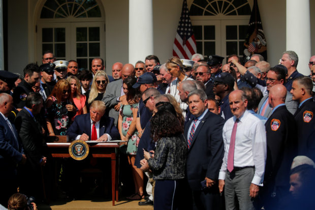 New York City first responders and guests look on as U.S. President Donald Trump signs the "Permanent Authorization of the September 11th Victim Compensation Fund Act" during a signing ceremony in the Rose Garden of the White House in Washington, U.S., July 29, 2019. (REUTERS/Carlos Barria)