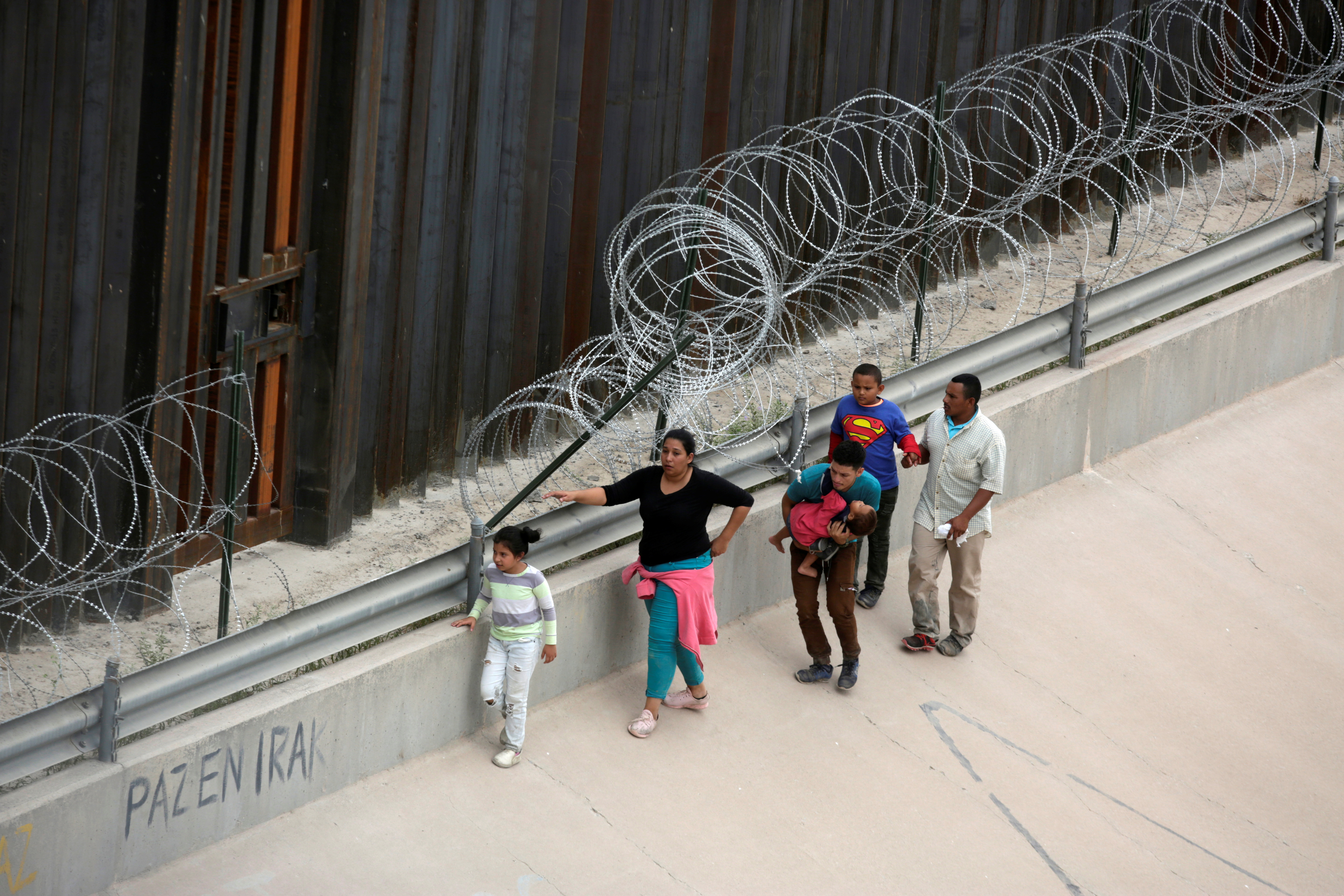 Migrants walk along the border fence after crossing illegally into El Paso, Texas, U.S. as seen from Ciudad Juarez