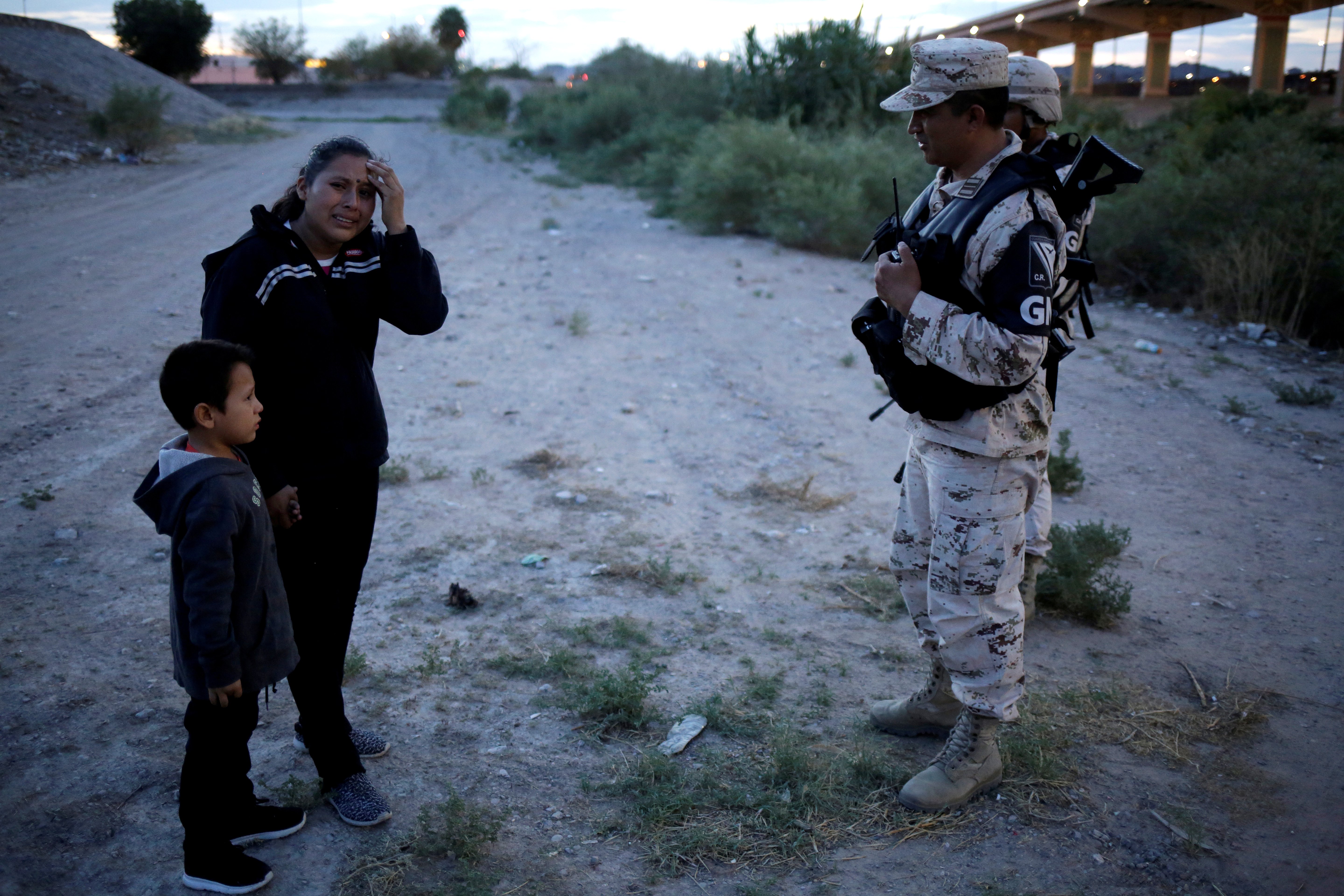 Guatemalan migrant Ledy Perez reacts while holding hands with her son Anthony while asking to members of the Mexican National Guard to let them cross into the United States, as seen from Ciudad Juarez, Mexico July 22, 2019. REUTERS/Jose Luis Gonzalez