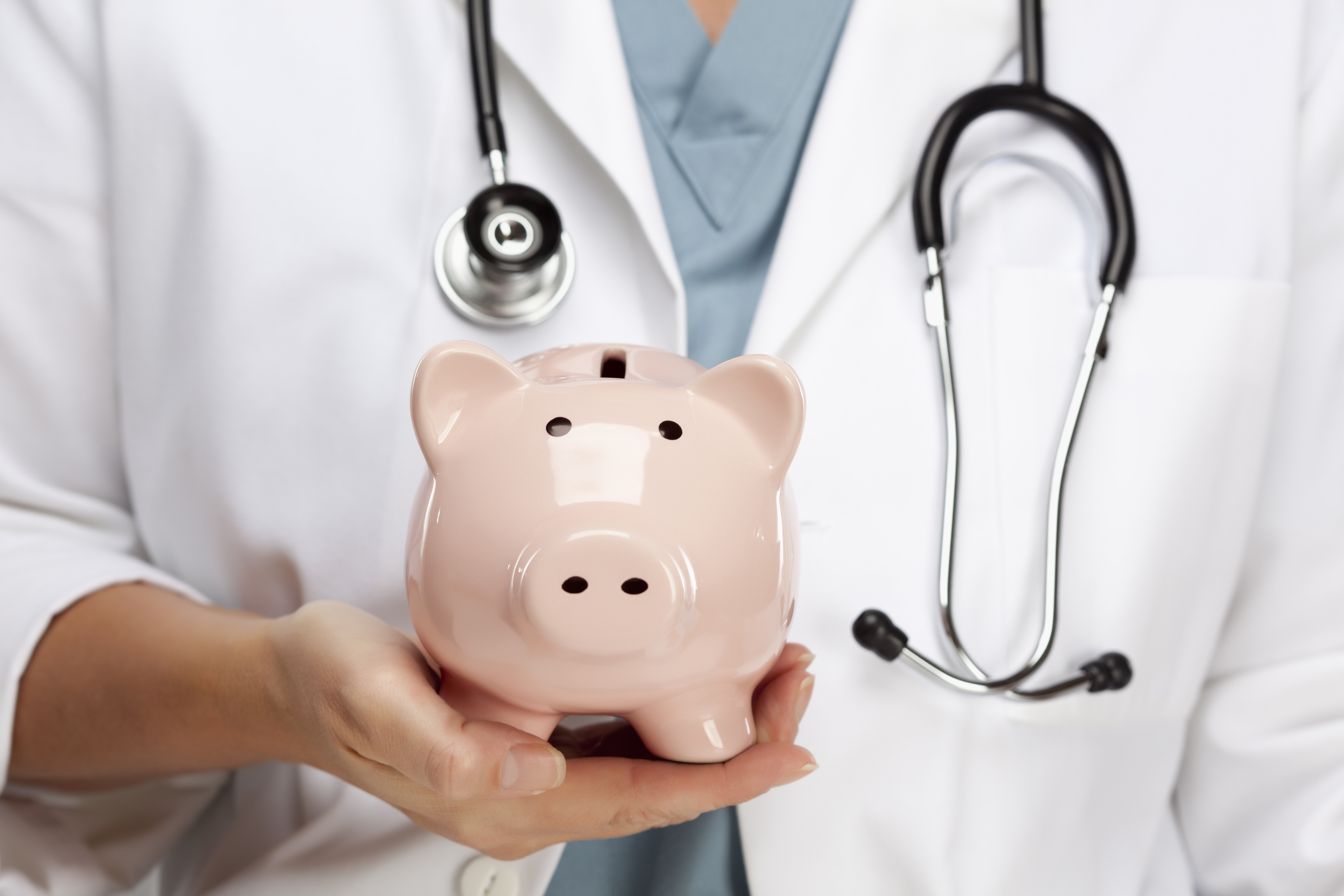 A doctor holds a piggy bank. Shutterstock image via Andy Dean Photography