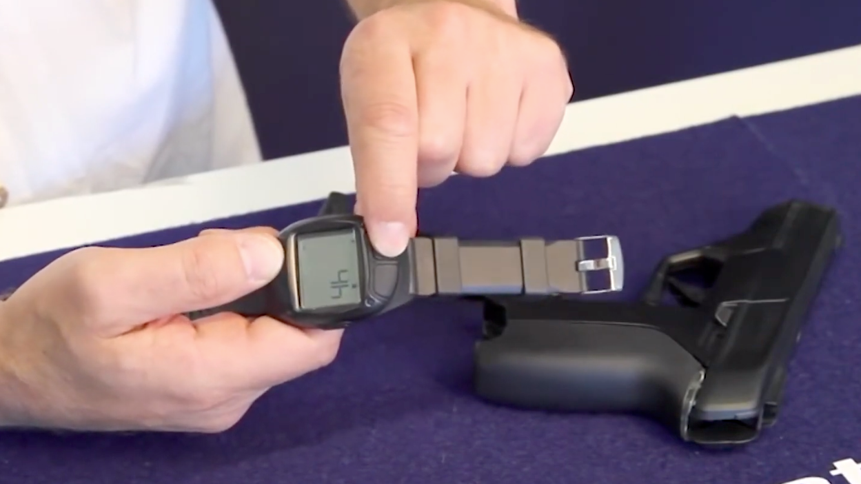 Armatix employee holds a smart gun by the company at the Armatix headquarters in Munich May 14, 2014. The gun is implanted with an electronic chip that allows it to be fired only if the shooter is wearing a watch that communicates with it through a radio signal within 10 inches. Photo Youtube screenshot courtesy of NJTV News.