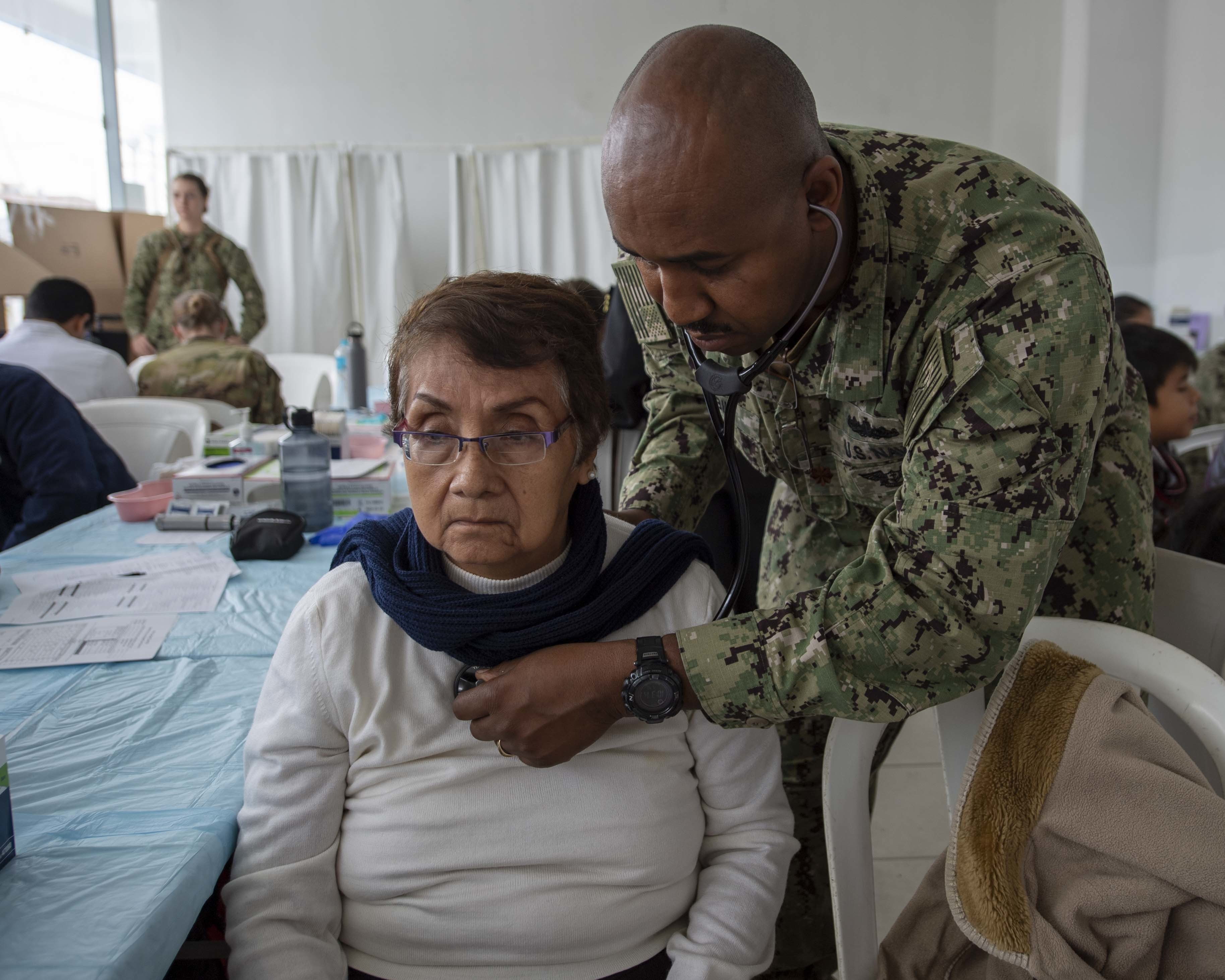 Lt. Cmdr. Jack Eric Tobin, a Navy nurse, assigned to the hospital ship USNS Comfort (T-AH 20), checks a patient’s vital signs at a temporary medical treatment site near Callao, Peru, on July 10, 2019. (U.S. Navy photo by Mass Communication Specialist 3rd Class Kryzentia Richards)