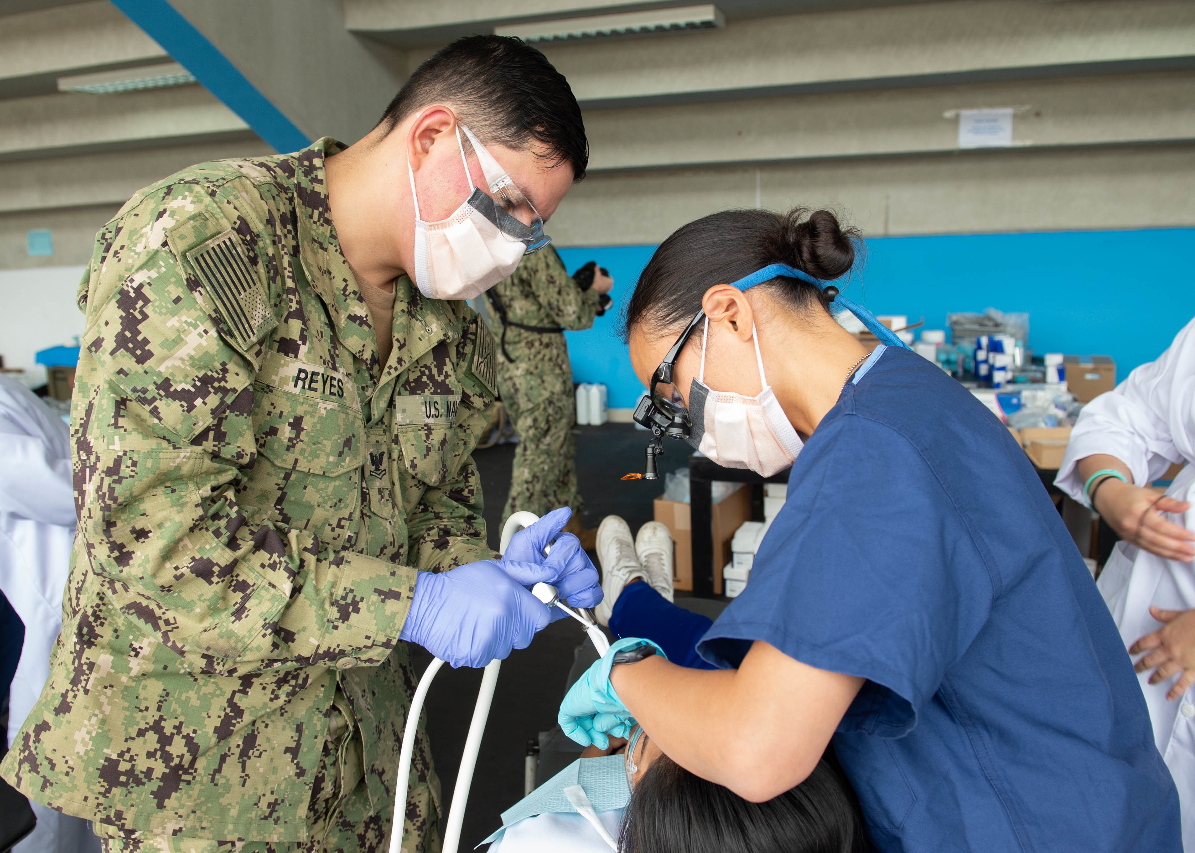 Hospital Corpsman 2nd Class Jose L. Reyes, from Lancaster, Calif., assigned to the hospital ship USNS Comfort (T-AH 20), left, and Lt. Vy Vy Vu (right), a U.S. Public Health Service dentist, treat a patient for dental care at a temporary medical site near Callao, Peru, on July 9, 2019. (U.S. Navy photo by Mass Communication Specialist 3rd Class Maria G. Llanos)