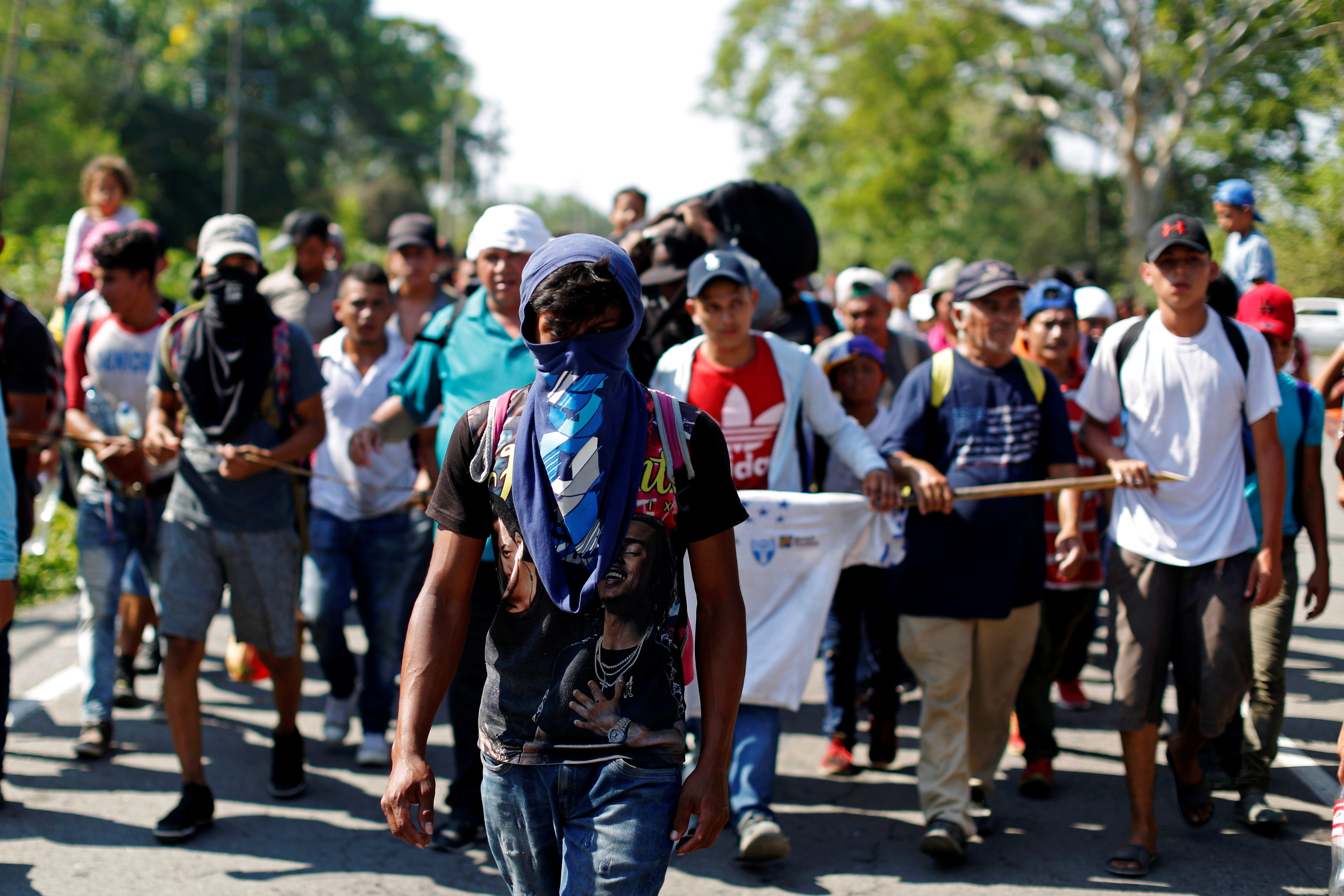 People belonging to a caravan of migrants from Honduras en route to the United States, walk on a highway in Metapa