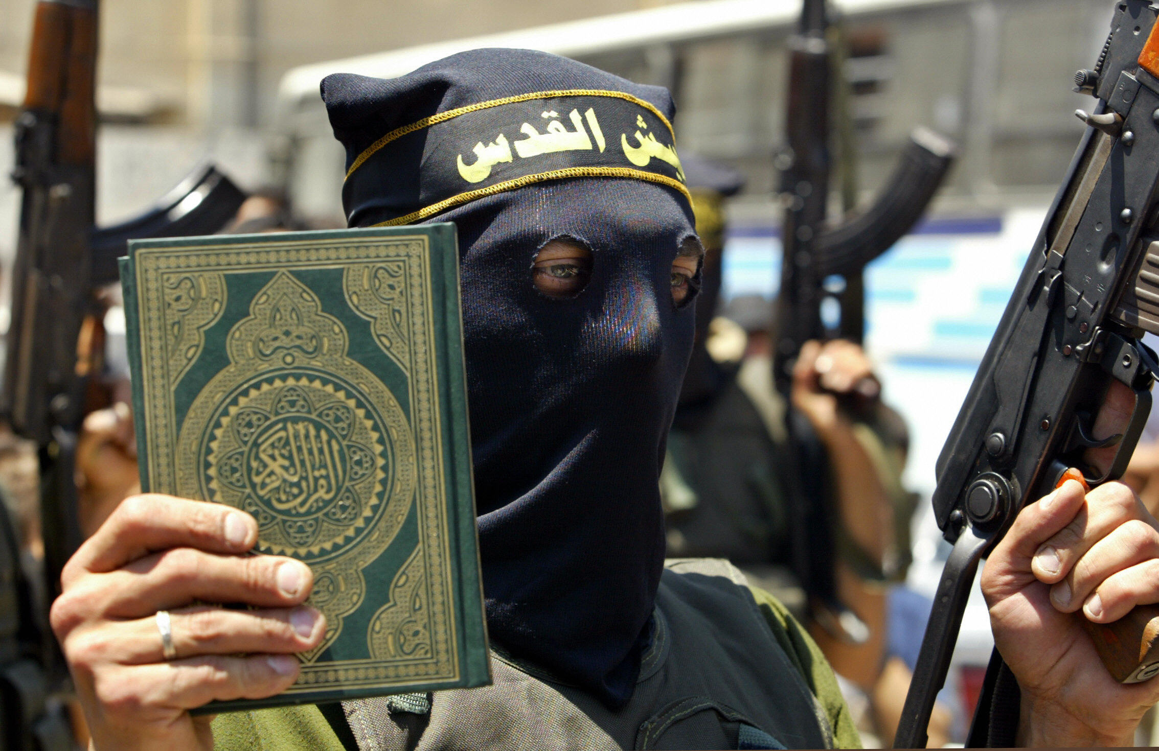 An Islamic Jihad militant holds up a copy of the Koran in one hand and an automatic rifle in the other during a rally in Beit Lahia in the northern Gaza Strip, 10 June 2005. (MOHAMMED ABED/AFP/Getty Images)