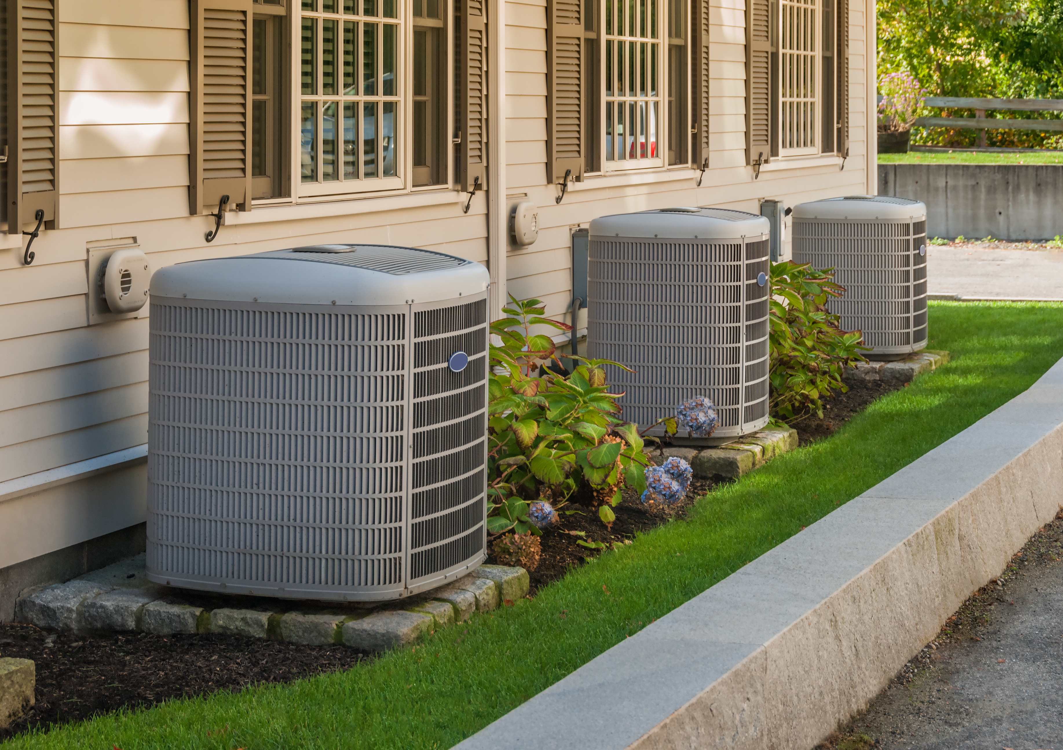 Air conditioning inverters are pictured on the side of a condo. Shutterstock image via Christian Delbert