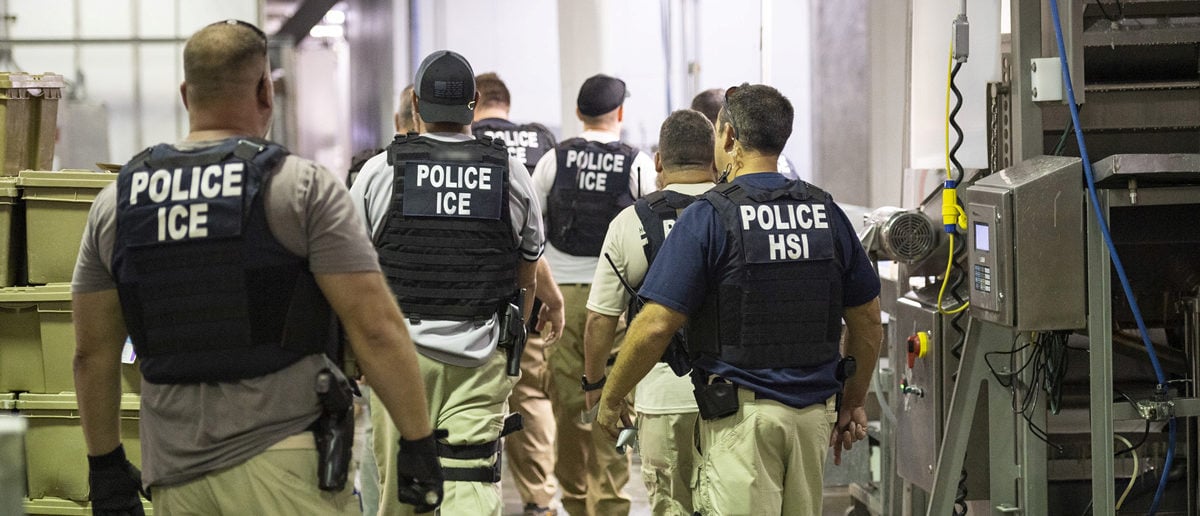 Homeland Security Investigations (HSI) officers from Immigration and Customs Enforcement (ICE) look on after executing search warrants and making some arrests at an agricultural processing facility in Canton
