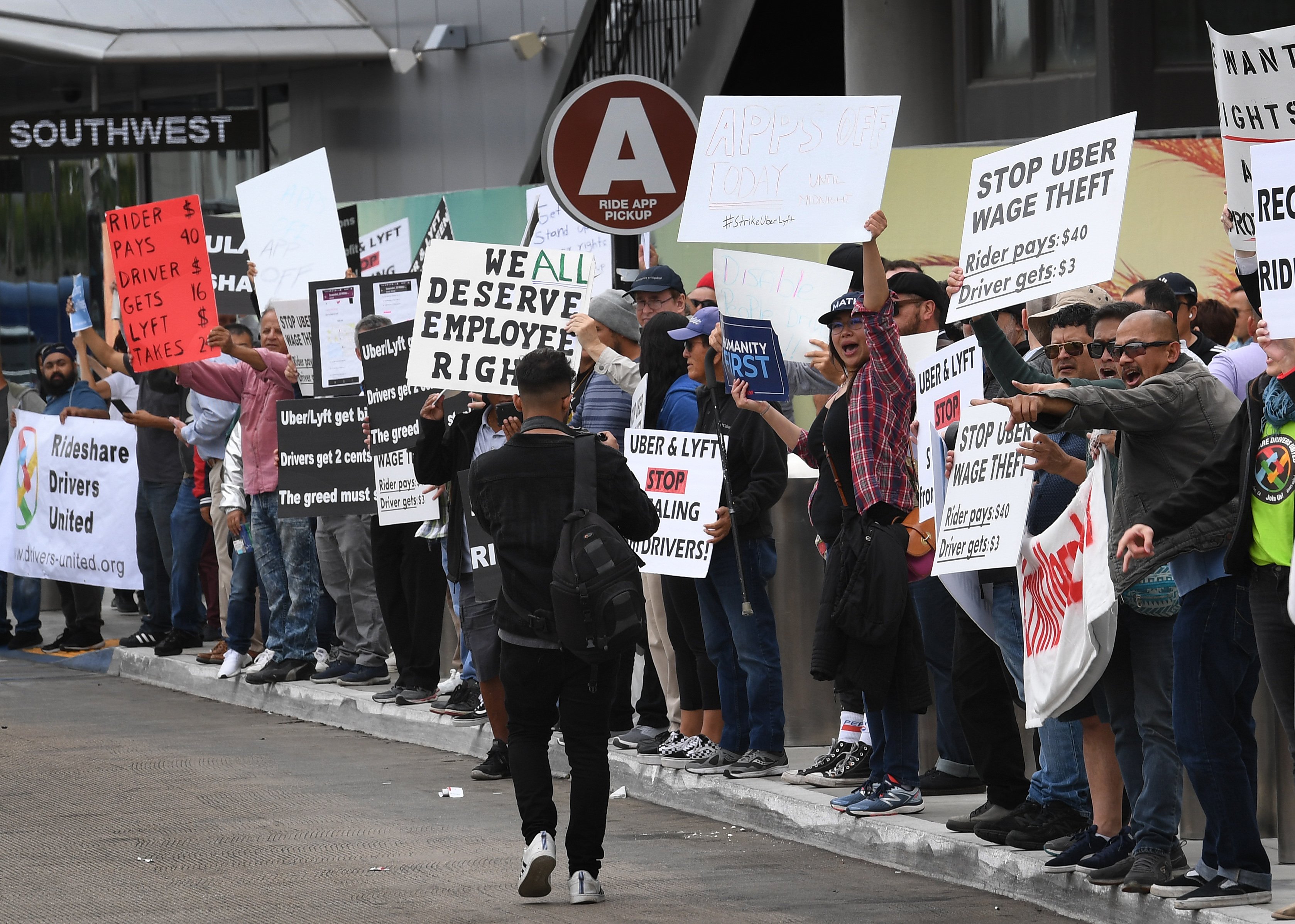 Rideshare drivers for Uber and Lyft stage a strike and protest at the LAX International Airport, over what they say are unfair wages in Los Angeles, California on May 8, 2019. - One of the early promises of the ride-hailing era ushered in by Uber and Lyft was that the new entrants would complement public transit, reduce car ownership and help alleviate congestion. But a new study on San Francisco has found the opposite may be in fact be true: far from reducing traffic, the companies increased delays by 40 percent as commuters ditched buses or walking for mobile-app summoned rides. (Photo by Mark RALSTON / AFP) (Photo credit should read MARK RALSTON/AFP/Getty Images)