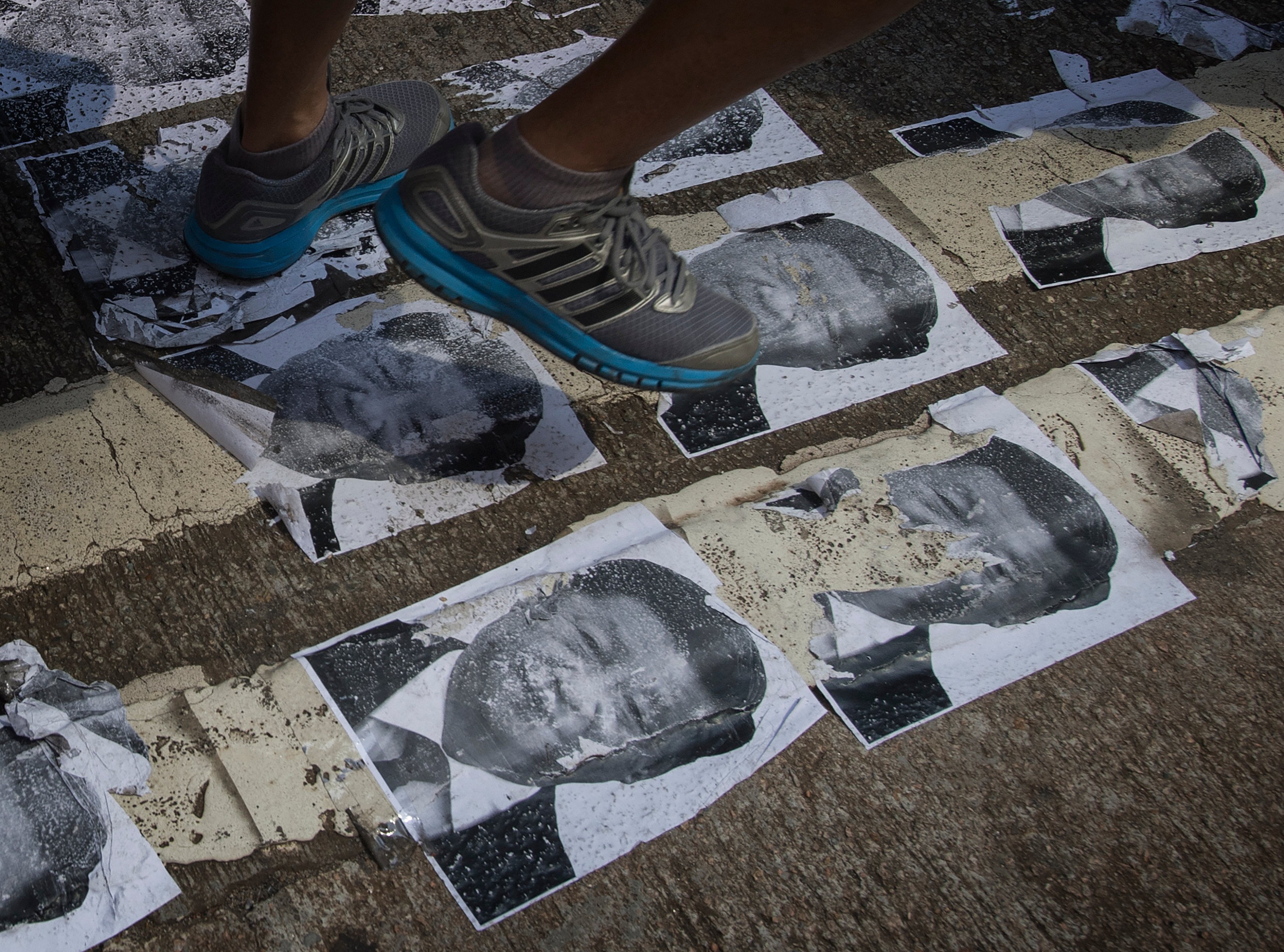 Protesters walk on an image of Chinese President Xi Jinping in the Causeway Bay area in Hong Kong on October 1, 2019, as the city observes the National Day holiday to mark the 70th anniversary of communist China's founding. - Strife-torn Hong Kong on October 1 marked the 70th anniversary of communist China's founding with defiant "Day of Grief" protests and fresh clashes with police as pro-democracy activists ignored a ban and took to the streets across the city. (Photo by Mark RALSTON / AFP) (Photo credit should read MARK RALSTON/AFP/Getty Images)