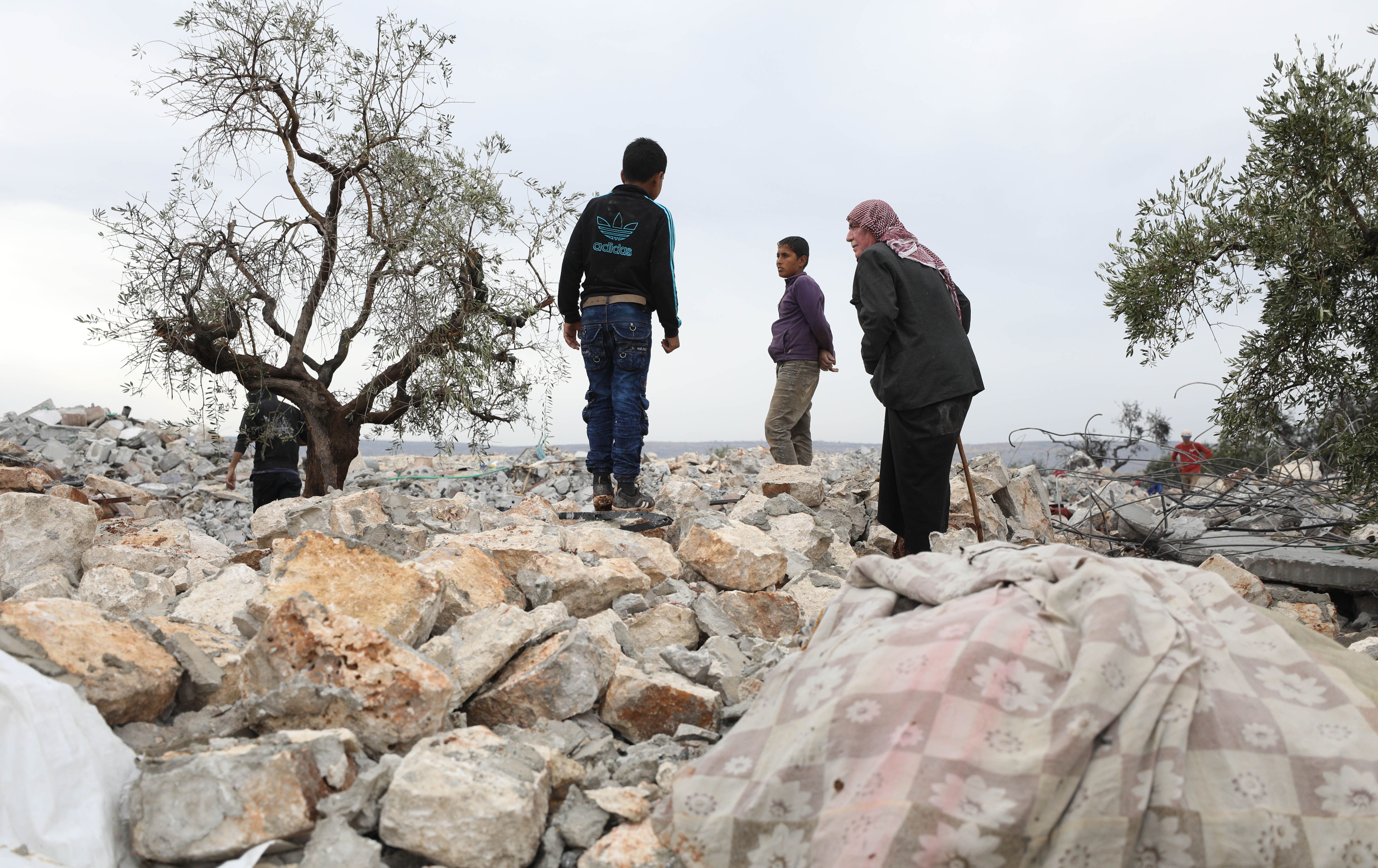 A picture taken on October 28, 2019 shows Syrians sifting through the rubble at the site of a suspected US-led operation against Islamic State (IS) chief Abu Bakr al-Baghdadi the previous day, on the edge of the small Syrian village of Barisha in the country's opposition-held northwestern Idlib province. - US President Donald Trump announced that Baghdadi, the elusive leader of the jihadist group and the world's most wanted man, was killed in the early hours of Octobe 27 in an overnight US raid near the village, located less than five kilometres from Turkey and controlled by the dominant jihadist group Hayat Tahrir al-Sham, an organisation that includes former operatives from Al-Qaeda's Syria affiliate. (Photo by Omar HAJ KADOUR / AFP) (Photo by OMAR HAJ KADOUR/AFP via Getty Images)
