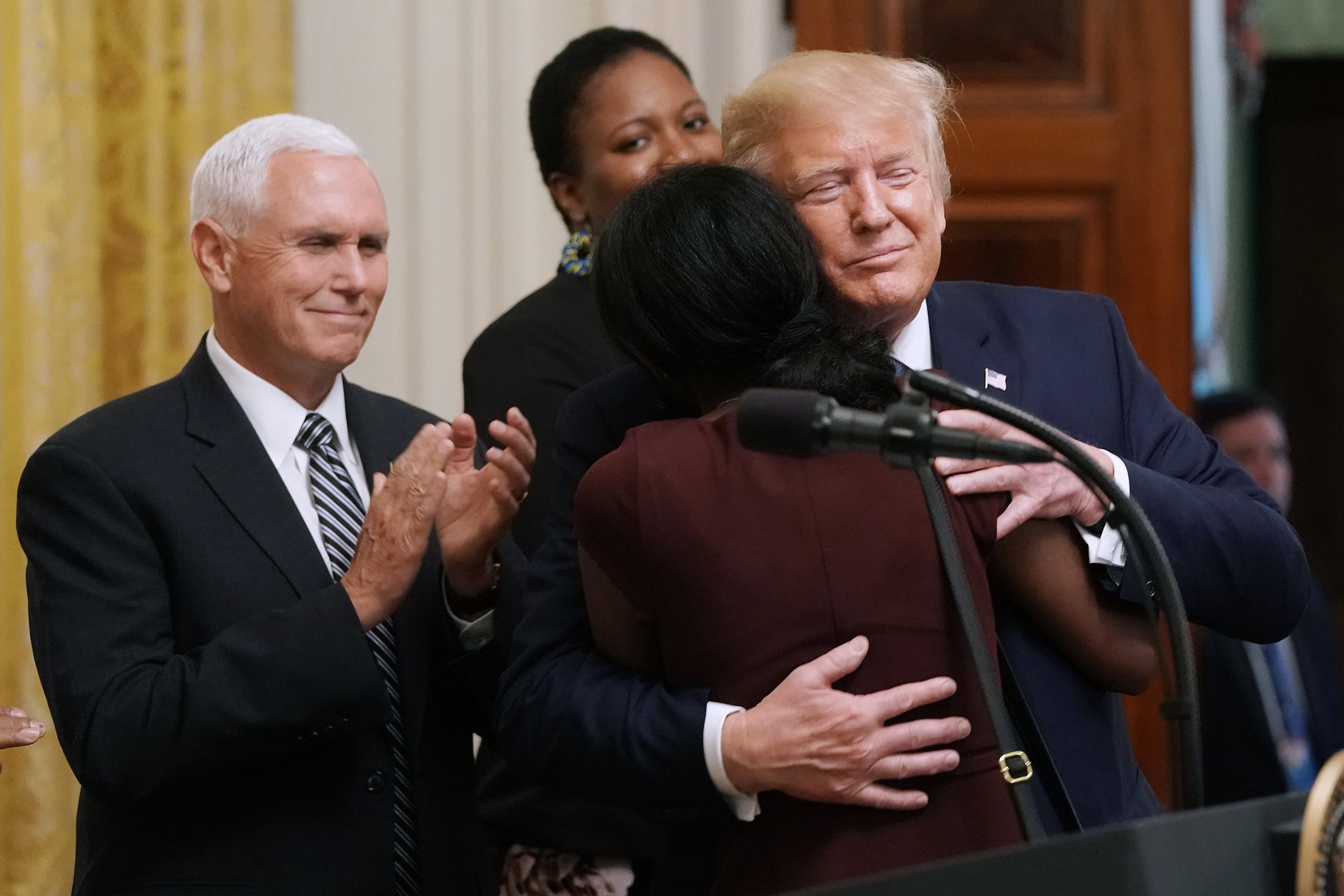 President Donald Trump embraces a woman he invited on stage to pray as Vice President Mike Pence looks on during an event for the Young Black Leadership Summit in the East Room of the White House October 04, 2019 in Washington, DC. Organized by the conservative nonprofit political group Turning Points USA, the summit bills itself as a professional development, leadership training and networking opportunity. Chip Somodevilla/Getty Images