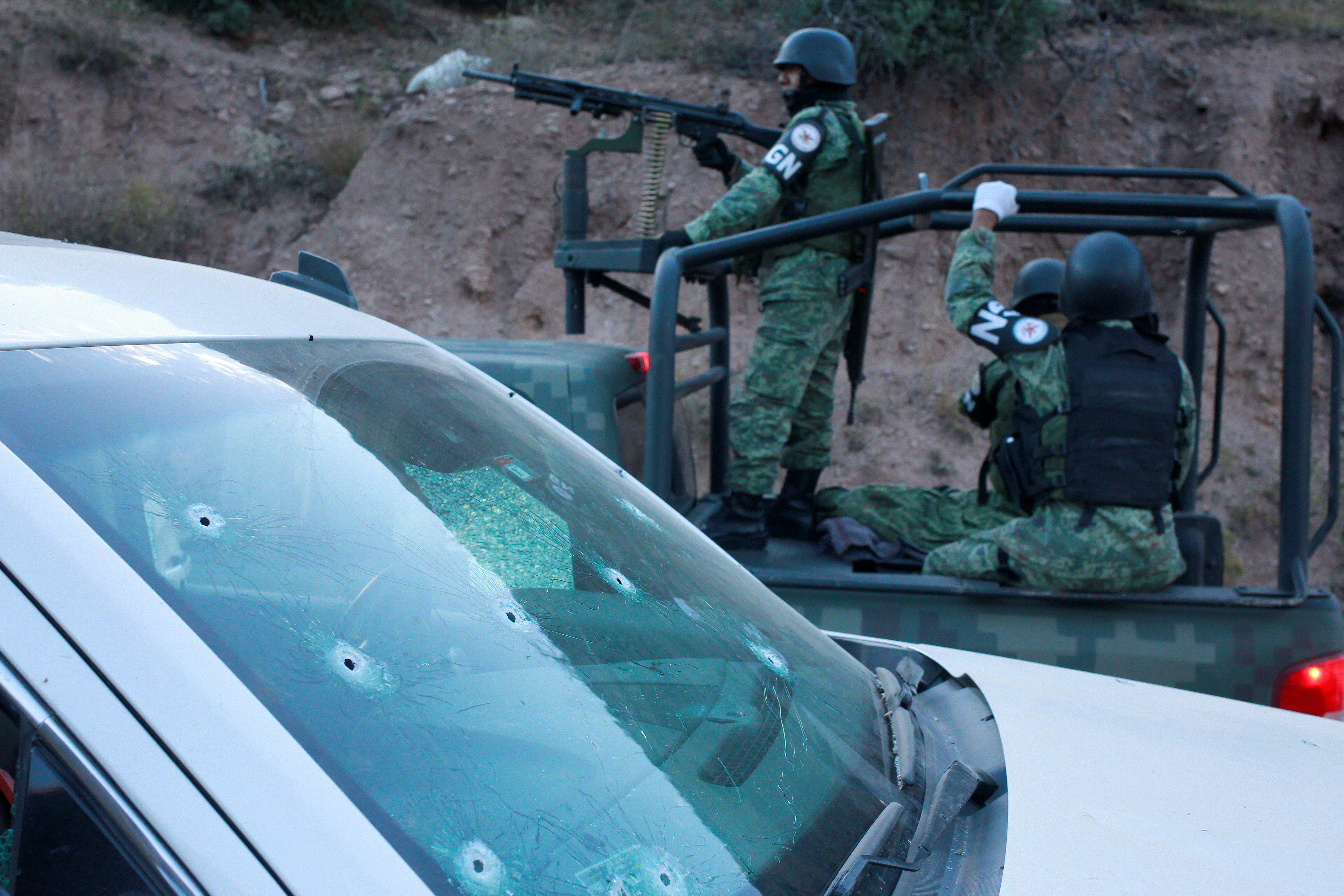 Soldiers assigned to Mexico's National Guard pass by a bullet-riddled vehicle belonging to Mexican-American Mormon families that were killed by unknown assailants, in Bavispe