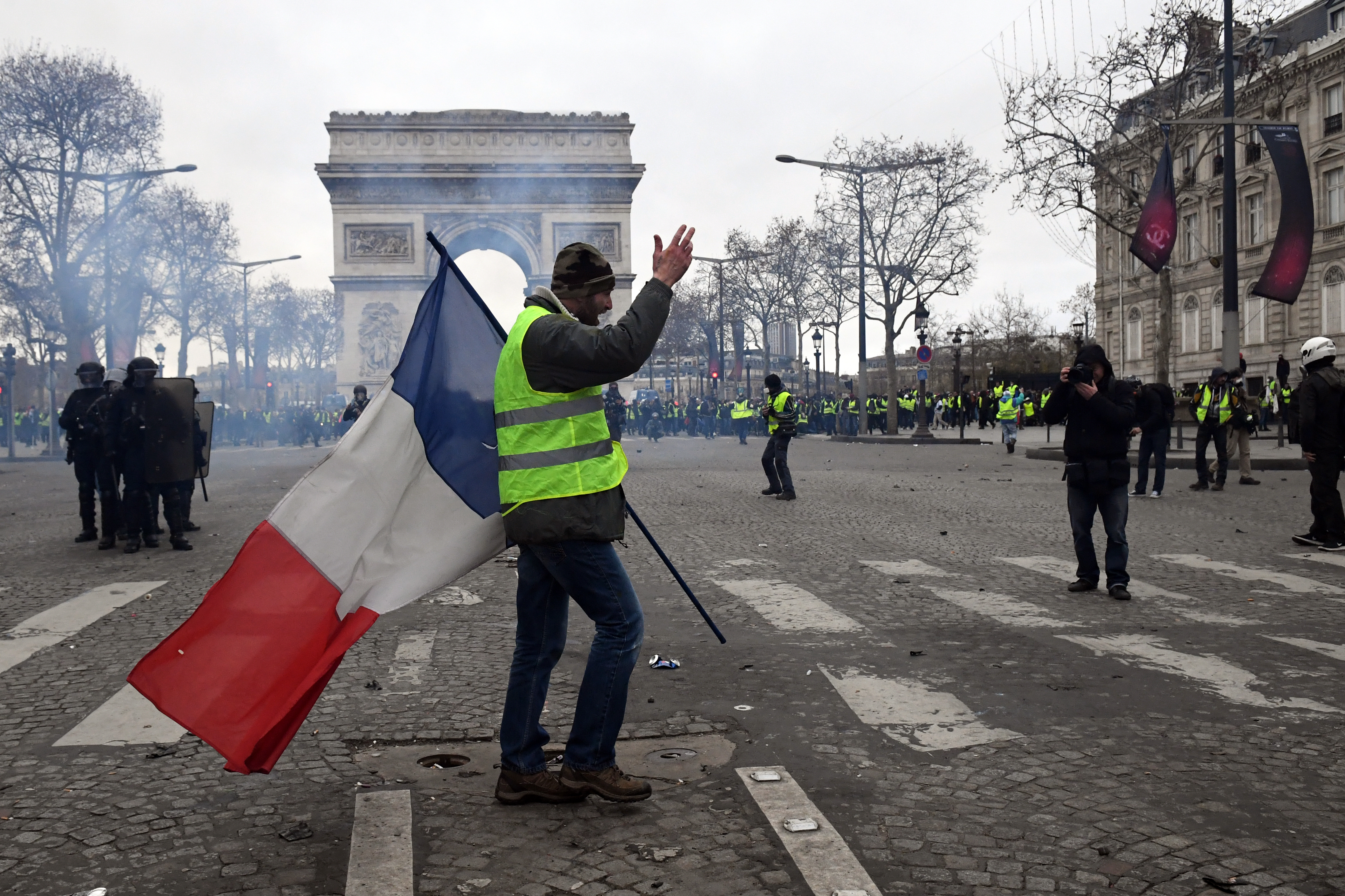 A protester walks walks with the french flag during the 'yellow vests' demonstration near the Arc de Triomphe on December 8, 2018 in Paris France. ''Yellow Vests' ("Gilet Jaunes" or "Vestes Jaunes") is a protest movement without political affiliation which was inspired by opposition to a new fuel tax. (Photo by Jeff J Mitchell/Getty Images)