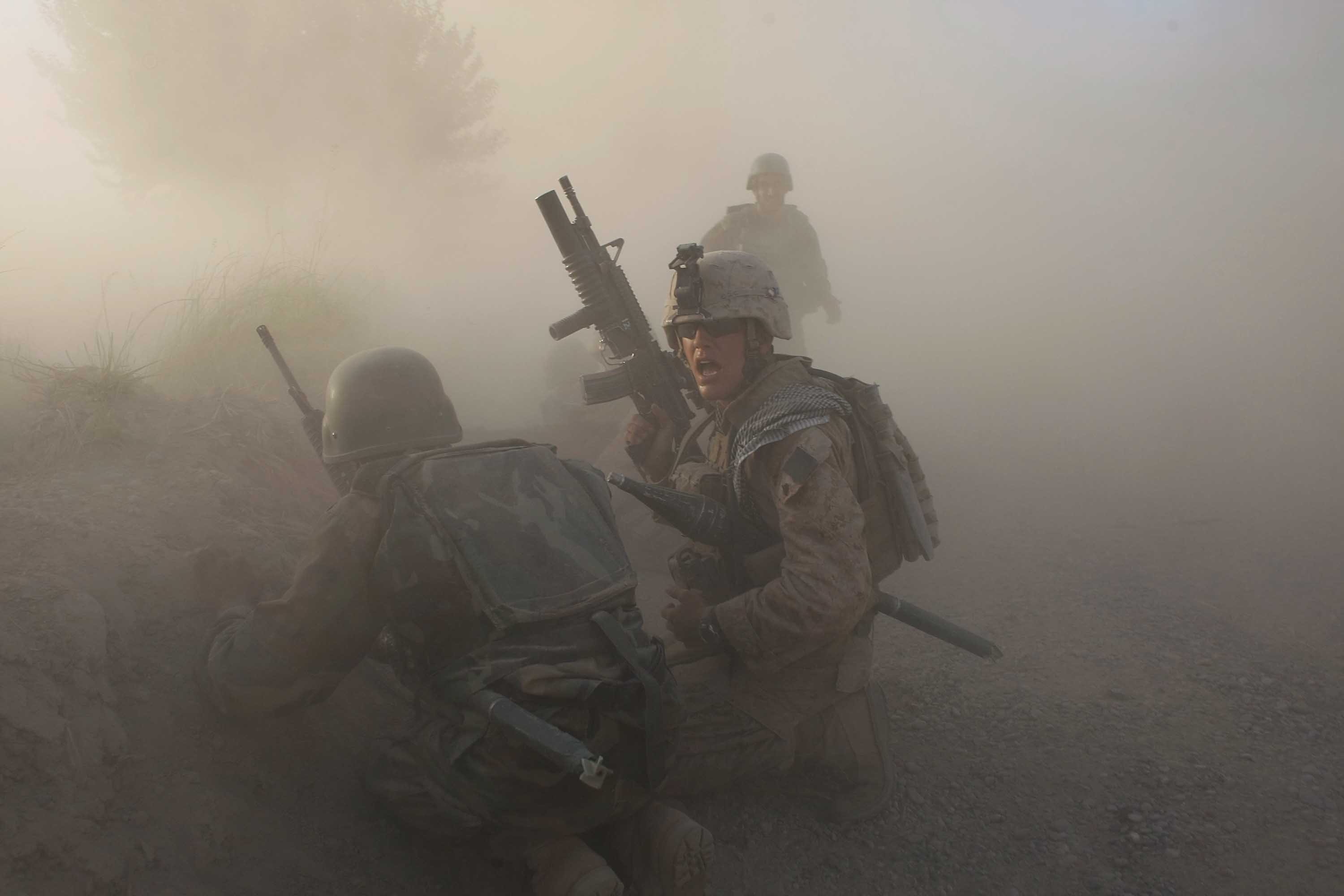 MIAN POSHTEH, AFGHANISTAN- JULY 17: A U.S. Marine with the 2nd Marine Expeditionary Brigade, RCT 2nd Battalion 8th Marines Echo Co. along with an Afghan soldier react as dust blankets the area after an IED exploded while they were under enemy fire on July 17, 2009 in Mian Poshteh, Afghanistan. The Marines are part of Operation Khanjari which was launched to take areas in the Southern Helmand Province that Taliban fighters are using as a resupply route and to help the local Afghan population prepare for the upcoming presidential elections. (Photo by Joe Raedle/Getty Images)