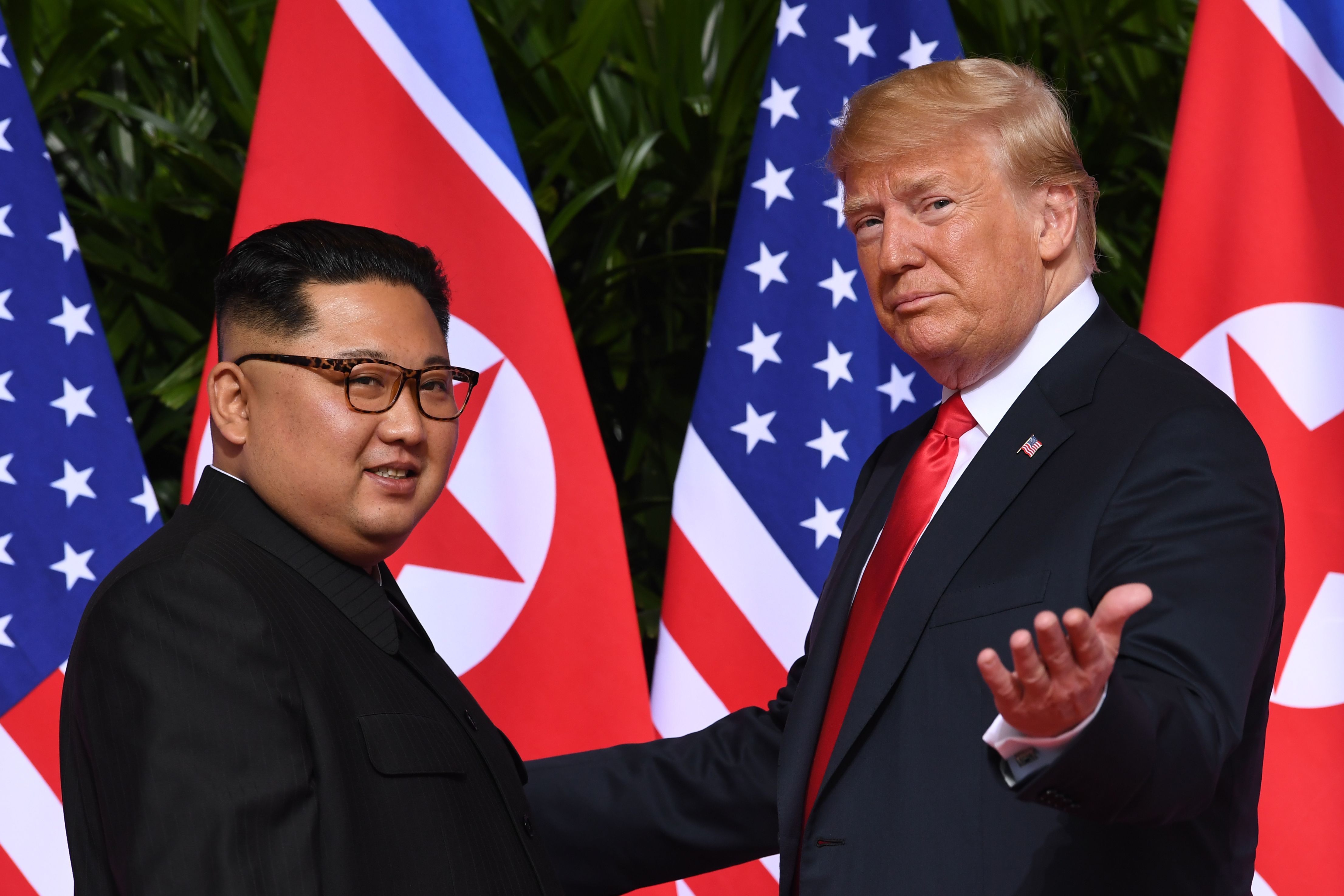 TOPSHOT - US President Donald Trump (R) gestures as he meets with North Korea's leader Kim Jong Un (L) at the start of their historic US-North Korea summit, at the Capella Hotel on Sentosa island in Singapore on June 12, 2018. - Donald Trump and Kim Jong Un have become on June 12 the first sitting US and North Korean leaders to meet, shake hands and negotiate to end a decades-old nuclear stand-off. (Photo by SAUL LOEB / AFP) (Photo credit should read SAUL LOEB/AFP via Getty Images)
