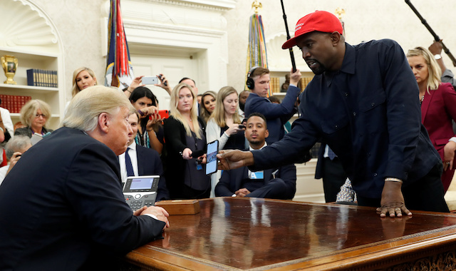 Rapper Kanye West shows President Donald Trump a picture on his mobile phone of what he described as a hydrogen powered airplane that should replace Air Force One during a meeting in the Oval Office at the White House in Washington, U.S., October 11, 2018. REUTERS/Kevin Lamarque 