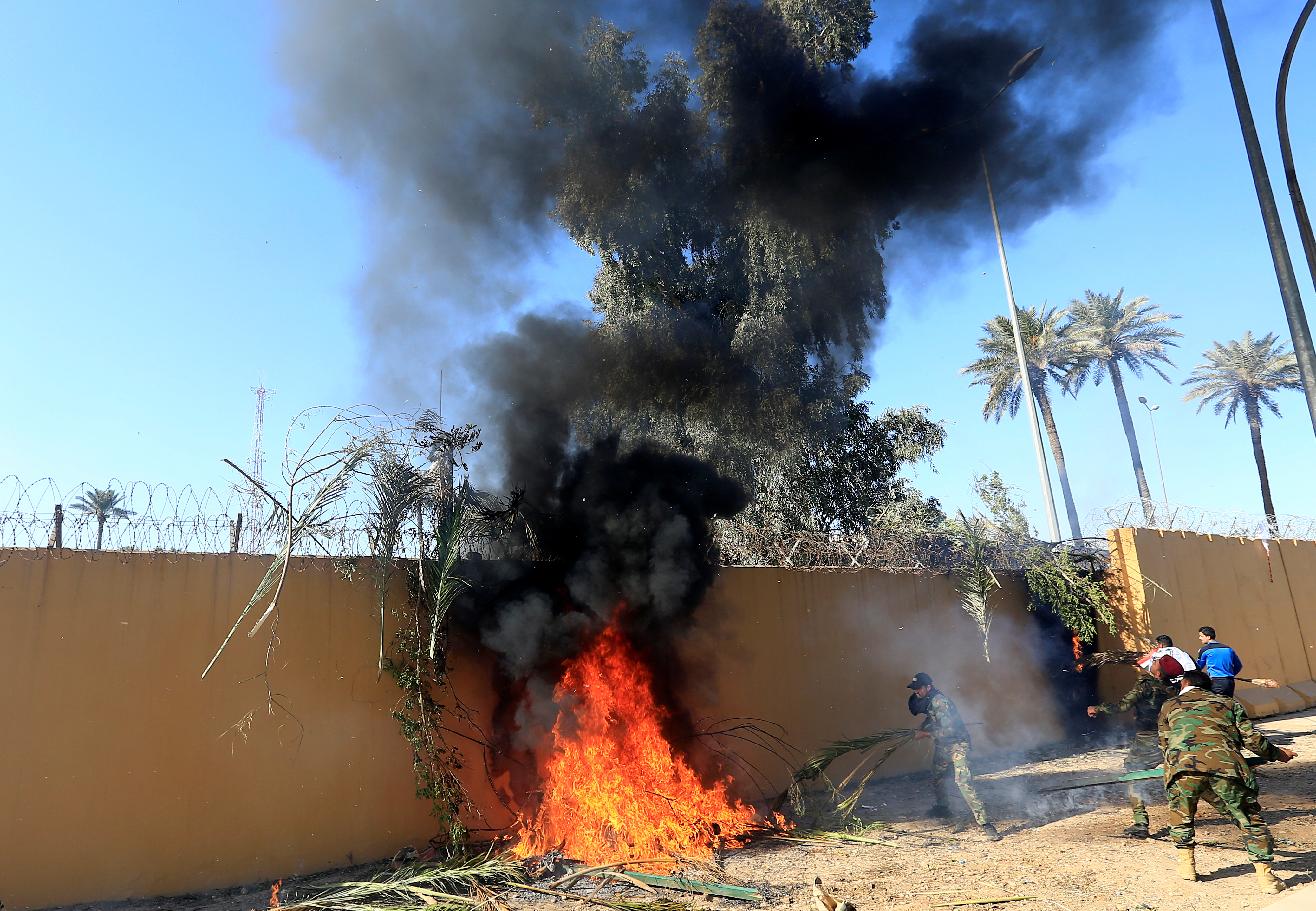 Hashd al-Shaabi (paramilitary forces) fighters set the U.S. Embassy wall on fire as they protest to condemn air strikes on their bases, in Baghdad, Iraq December 31, 2019. (REUTERS/Thaier al-Sudani)