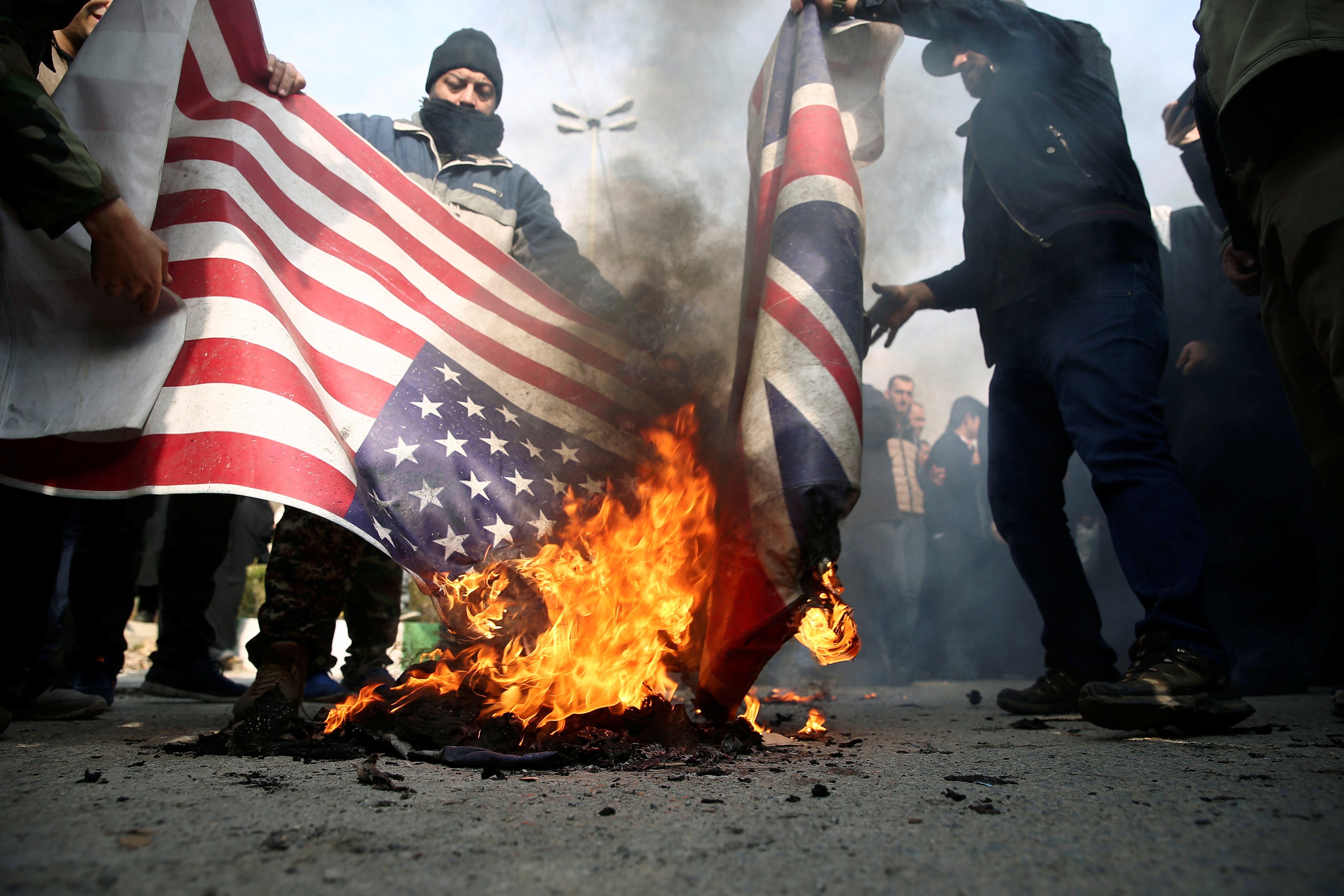 Demonstrators burn the U.S. and British flags during a protest against the assassination of the Iranian Major-General Qassem Soleimani, head of the elite Quds Force, and Iraqi militia commander Abu Mahdi al-Muhandis who were killed in an air strike in Baghdad airport, in Tehran, Iran January 3, 2020. WANA (West Asia News Agency)/Nazanin Tabatabaee via REUTERS
