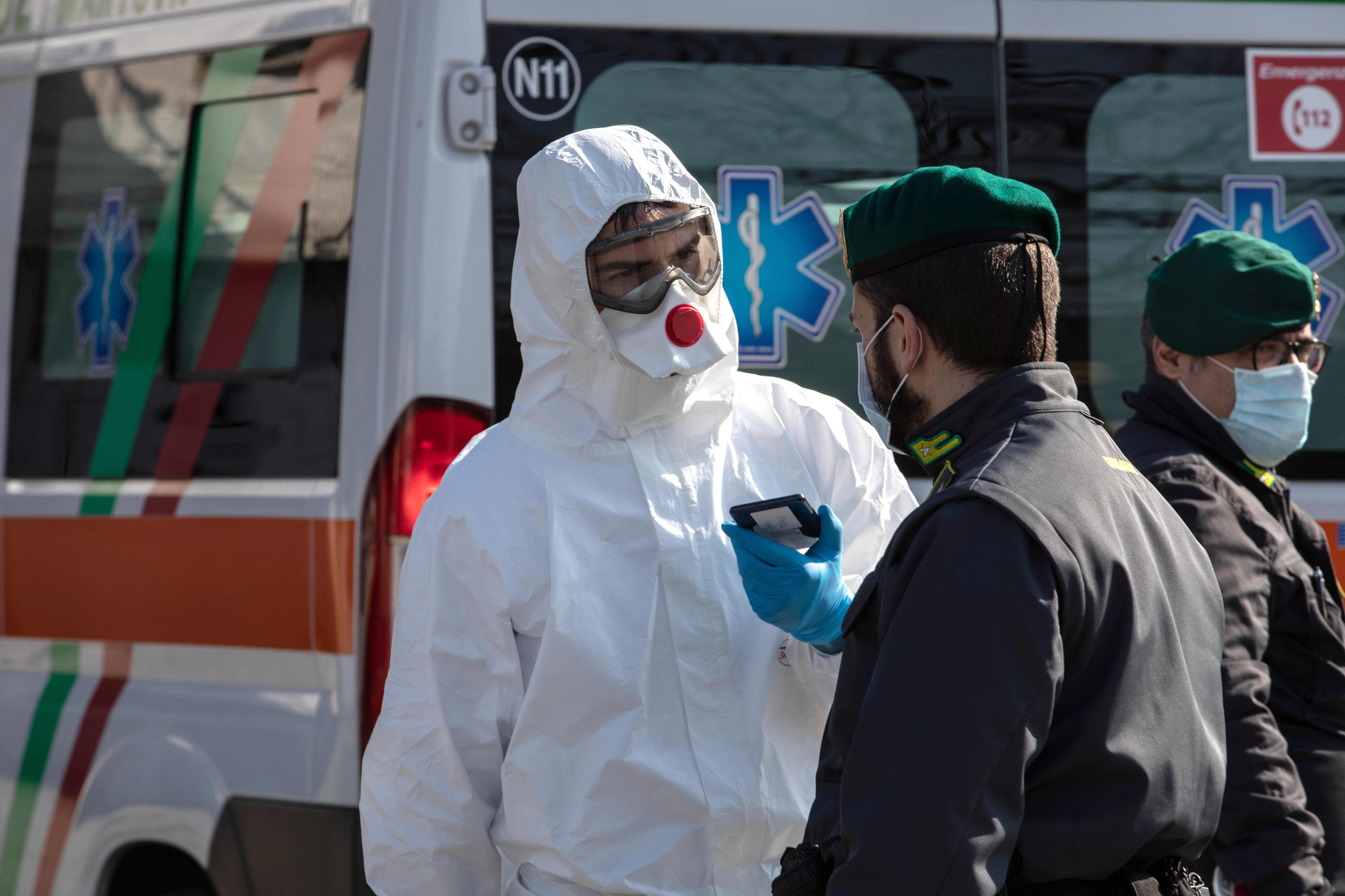 A rescue worker, wearing a protective suit, talks to an Italian Guardia di Finanza (Custom Plice) officer at a road block on February 24, 2020 in Casalpusterlengo, south-west Milan, Italy. Casalpusterlengo is one of the ten small towns placed under lockdown after coronavirus sparked infections throughout the Lombardy region.(Emanuele Cremaschi/Getty Images)