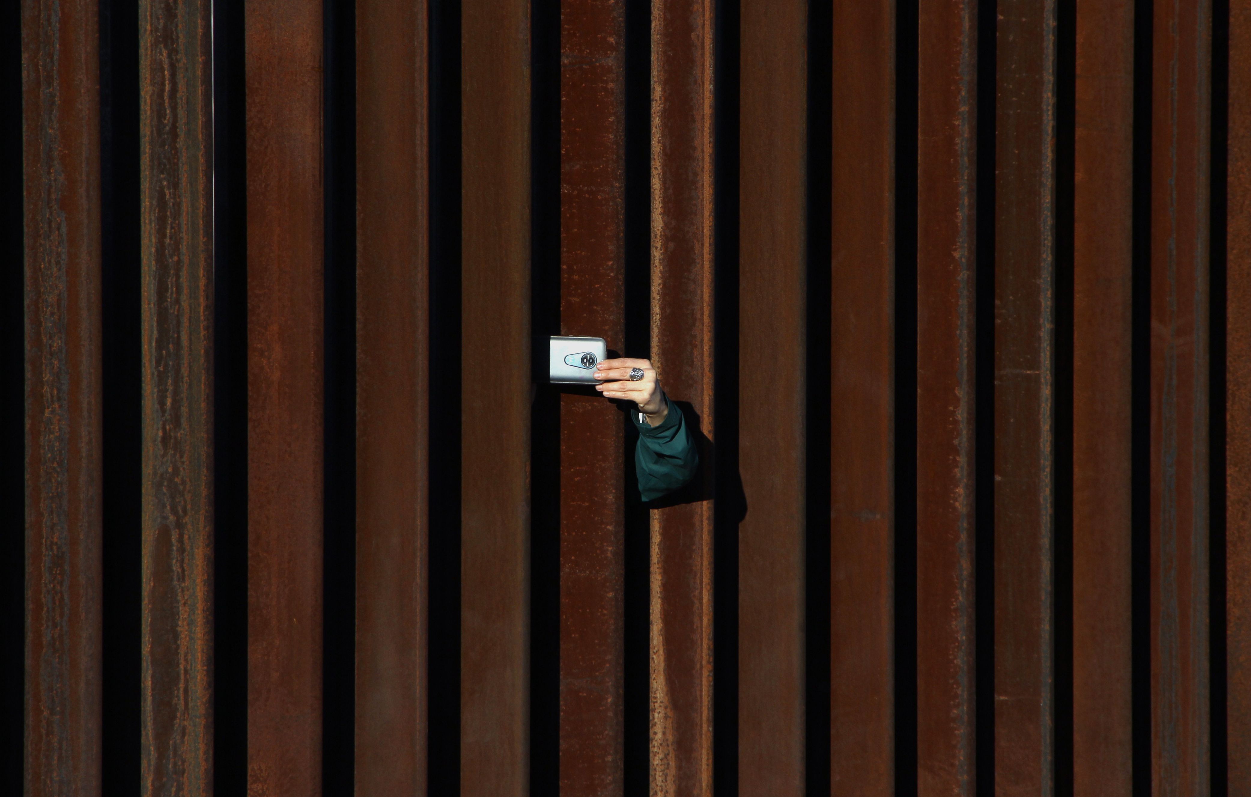 A woman in the United States takes a picture to Mexico through the border fence as residents of Anapra, a neighbourhood on the outskirts of Ciudad Juarez in Mexico, and other people attend a prayer with priests and bishops from both countries to ask for the migrants and people of the area, on February 26, 2019. - Built two years ago, the Anapra fence is one of several reinforced border barriers that the administration of US President Donald Trump calls the first sections of the wall. (HERIKA MARTINEZ/AFP via Getty Images)