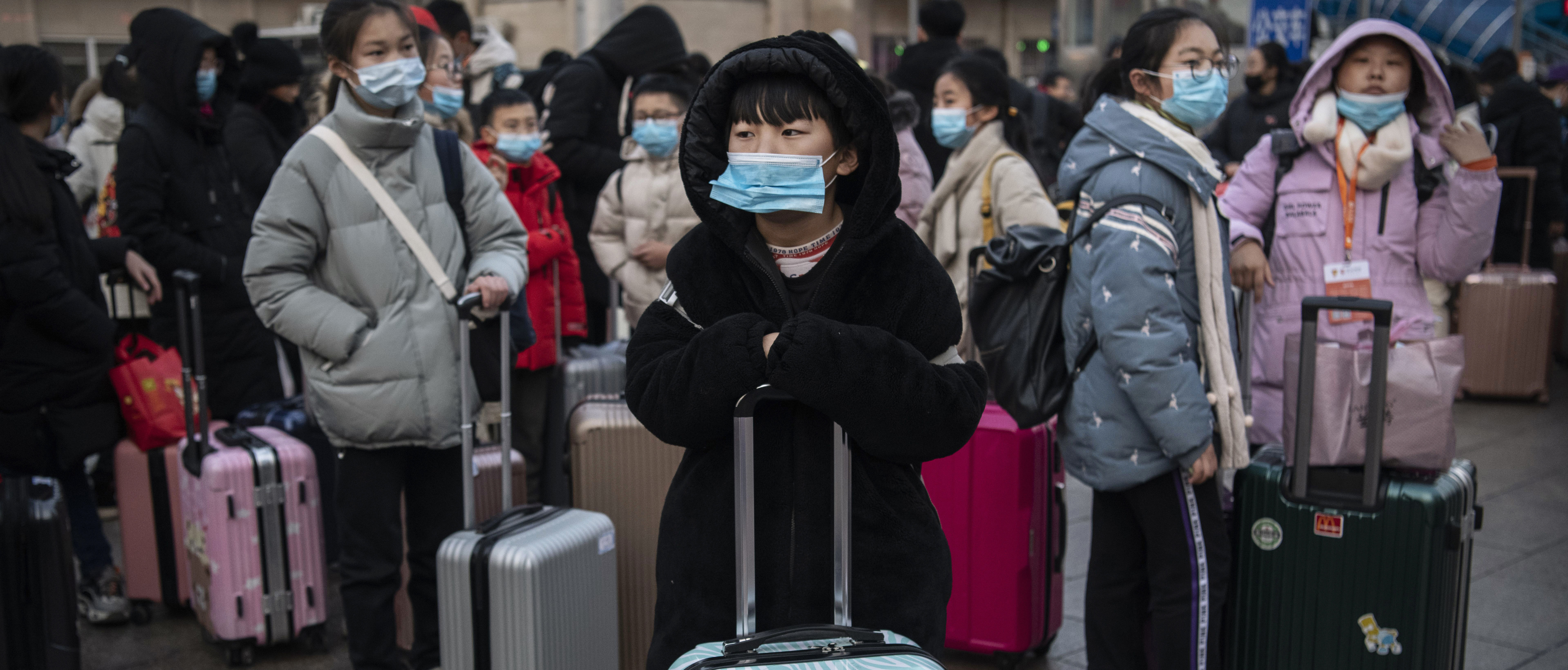 Chinese children wear protective masks as they wait to board trains at Beijing Railway station before the annual Spring Festival (Photo by Kevin Frayer/Getty Images)