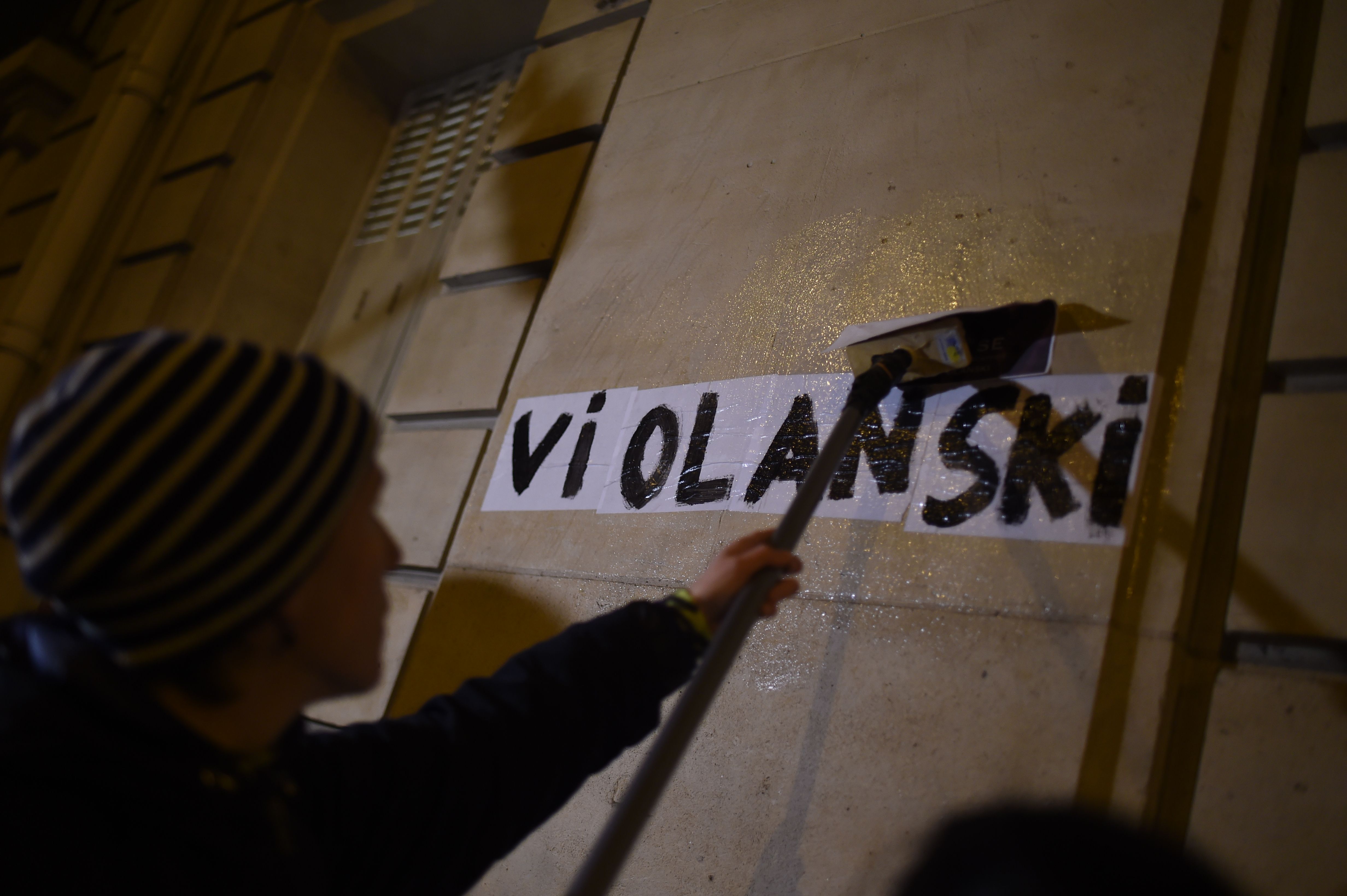 A feminist activist placards a poster with a play on words combining the word rape in French with the name of Polish-French filmmaker Roman Polanski near the Salle Pleyel venue, where the Cesar cinema awards ceremony is to be held the next day, on February 27, 2020, in Paris. - The academy organising France's Cesar awards is going through a crisis after the entire board resigned amid calls for reform and a row over the long-running Roman Polanski scandal. The Cesar Academy has been under fire since the end of January after Roman Polanski's film "An Officer and a Spy" (J'accuse) topped the list of nominations for this year's Cesar awards, due to be handed out on February 28. Polanski told AFP on February 27, 2020, he would not attend the ceremony French Oscars because he fears a "public lynching" by feminist activists. (Photo by LUCAS BARIOULET/AFP via Getty Images)