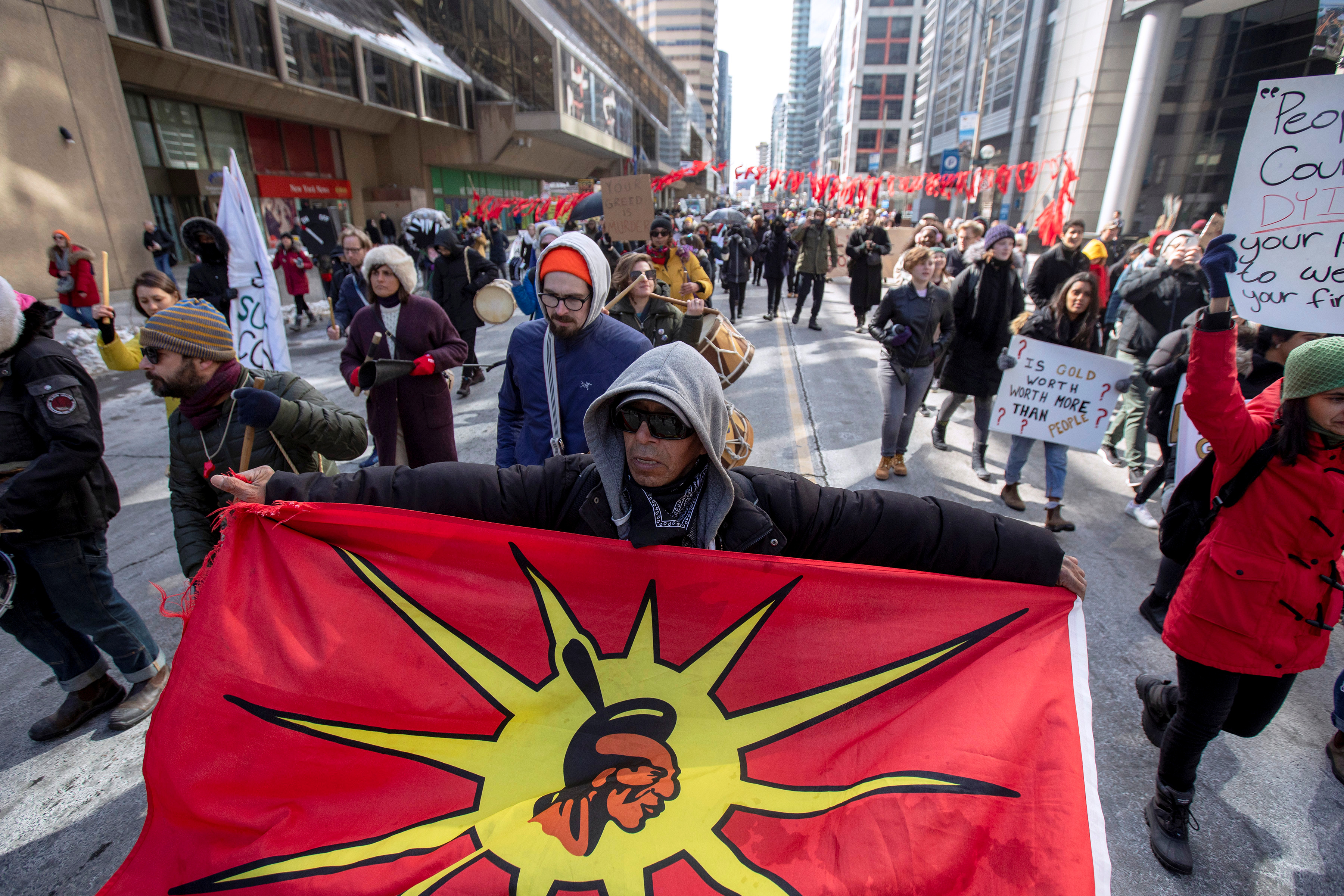 A protester holds a Mohawk Warrior Society flag as others march near the Prospectors & Developers Association of Canada (PDAC) convention to condemn mining practices in Toronto, Ontario, Canada March 1, 2020. REUTERS/Carlos Osorio 
