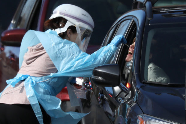 Health care worker tests people at a drive-thru testing station run by the state health department, for people who suspect they have novel coronavirus, in Denver
