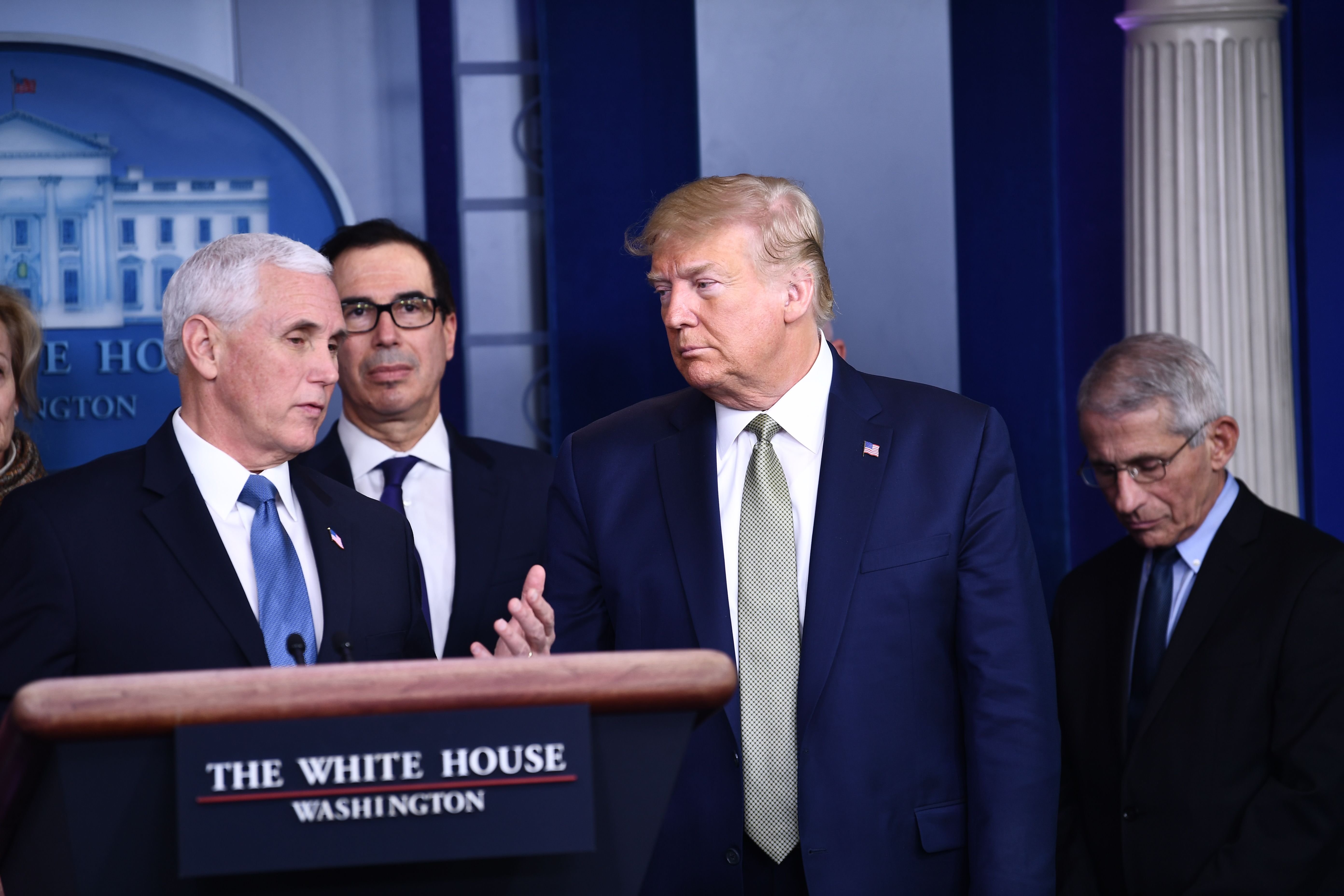 US President Donald Trump(R) listens to Vice President Mike Pence as they attend the daily press briefing on the Coronavirus pandemic situation at the White House on March 17, 2020 in Washington, DC. - The coronavirus outbreak has transformed the US virtually overnight from a place of boundless consumerism to one suddenly constrained by nesting and social distancing.The crisis tests all retailers, leading to temporary store closures at companies like Apple and Nike, manic buying of food staples at supermarkets and big-box stores like Walmart even as many stores remain open for business -- albeit in a weirdly anemic consumer environment (Photo by BRENDAN SMIALOWSKI/AFP via Getty Images)