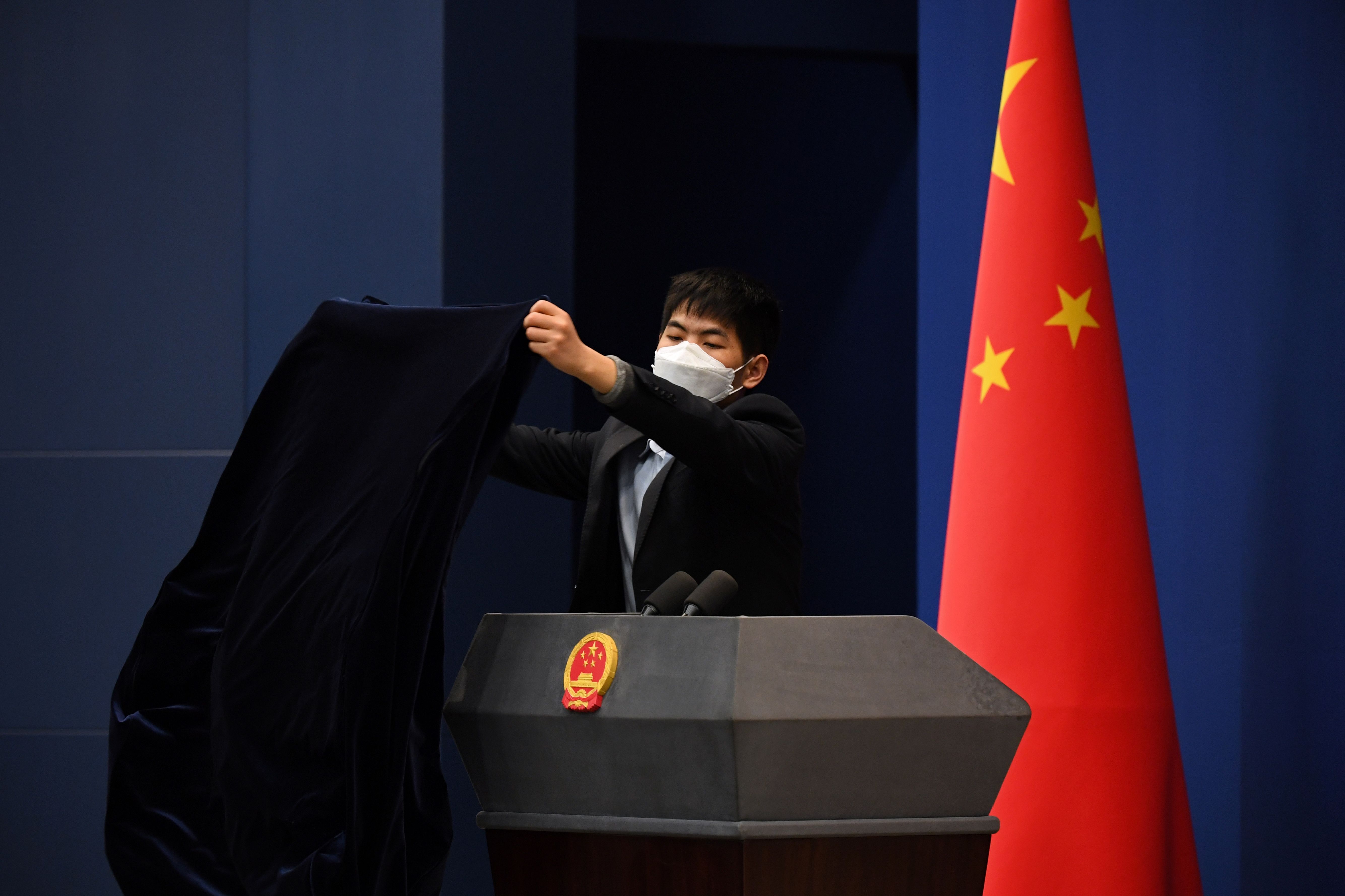 A worker wears a mask as a preventive measure against the COVID-19 coronavirus as he covers the podium after the daily media briefing at the Foreign Ministry in Beijing on March 18, 2020. (GREG BAKER/AFP via Getty Images)