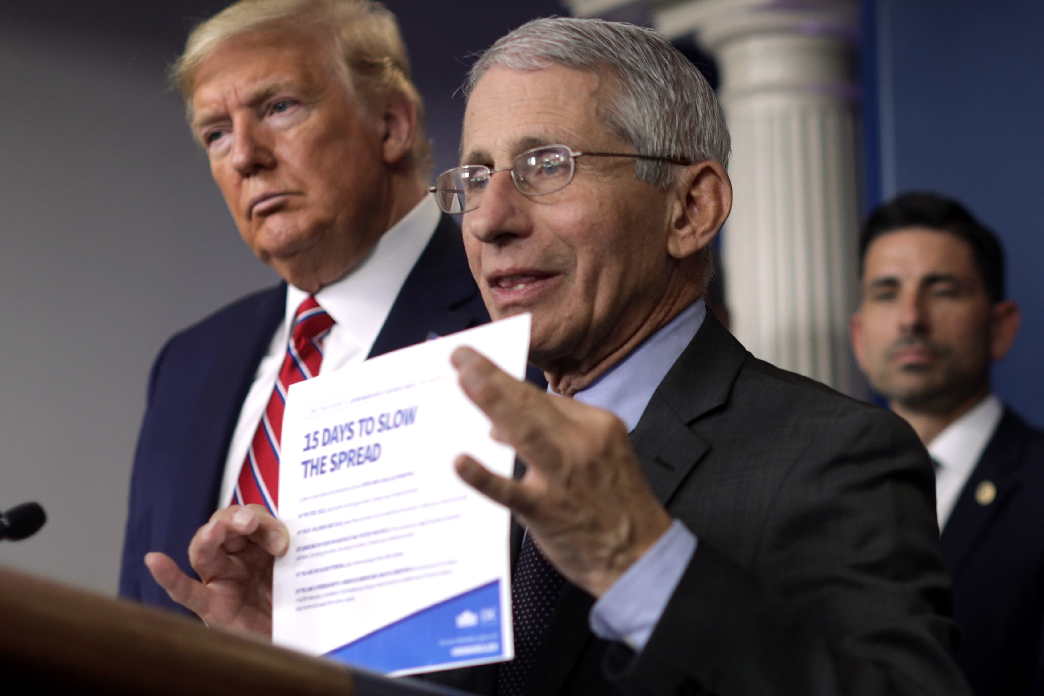 WASHINGTON, DC - MARCH 20: Director of the National Institute of Allergy and Infectious Diseases Dr. Anthony Fauci holds up the "15 Days to Slow the Spread" instruction as U.S. President Donald Trump looks on during a news briefing on the latest development of the coronavirus outbreak in the U.S. at the James Brady Press Briefing Room at the White House March 20, 2020 in Washington, DC. With deaths caused by the coronavirus rising and foreseeable economic turmoil, the Senate is working on legislation for a $1 trillion aid package to deal with the COVID-19 pandemic. President Trump announced that tax day will be delayed from April 15 to July 15. (Photo by Alex Wong/Getty Images)