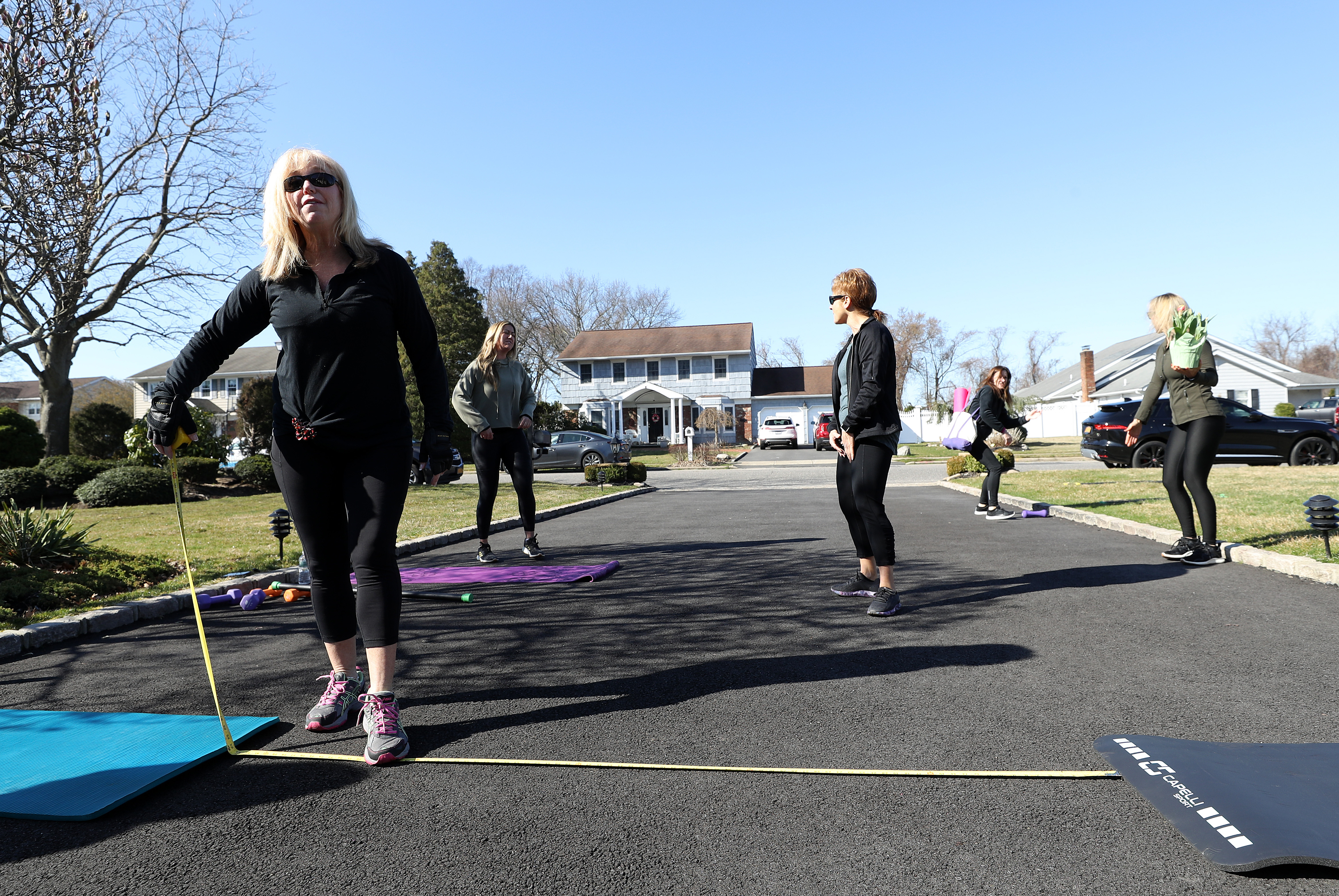 Veronica King of Sayville measures a distance of seven feet between mats prior to an outdoor class run by Fitness Instructor Jamie Benedik in the driveway of her home on March 26, 2020 in West Islip, New York. (Al Bello/Getty Images)