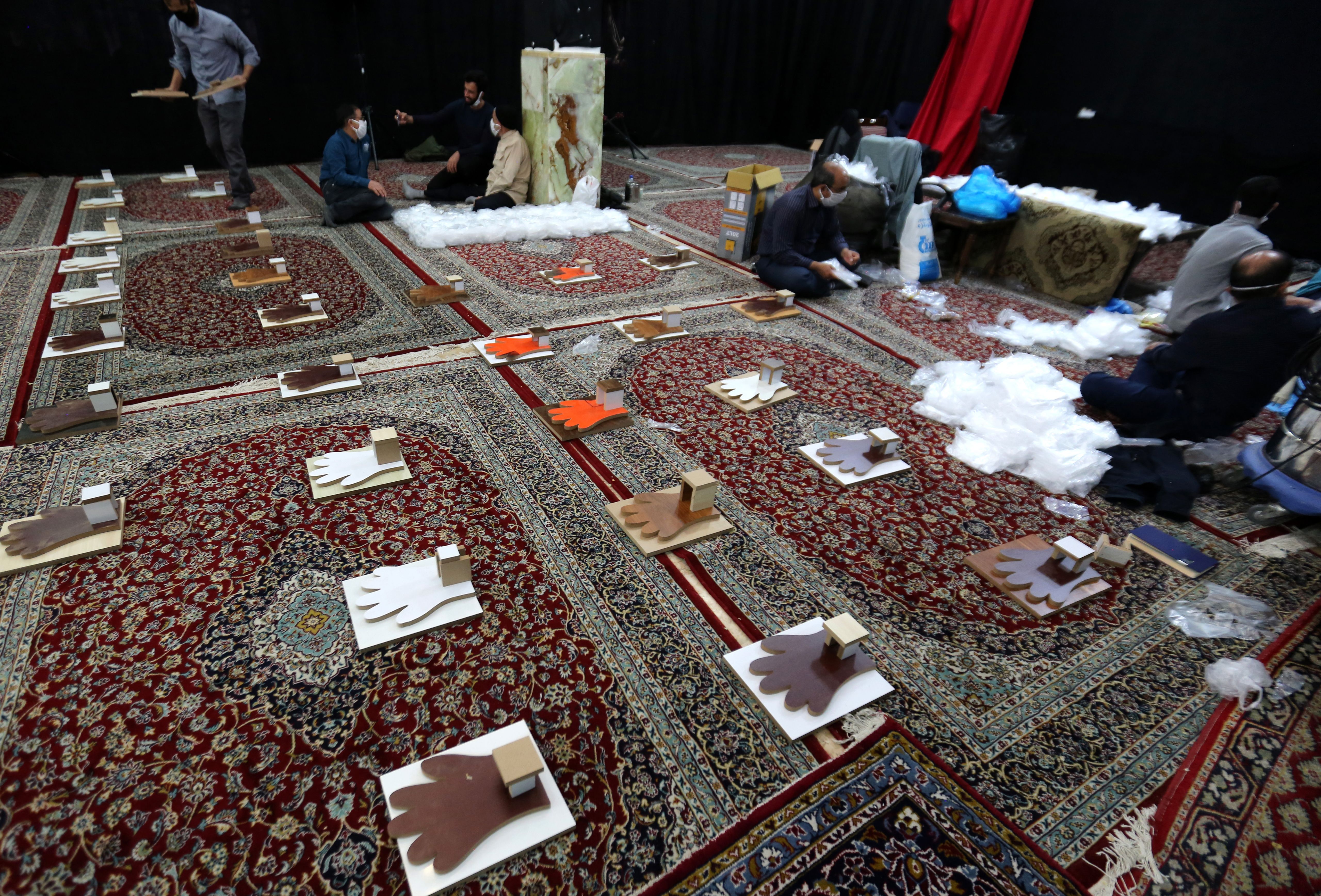 Iranian men, members of paramilitary organisation Basij, make protective gloves inside a mosque in the capital Tehran. (Photo by ATTA KENARE/AFP via Getty Images)