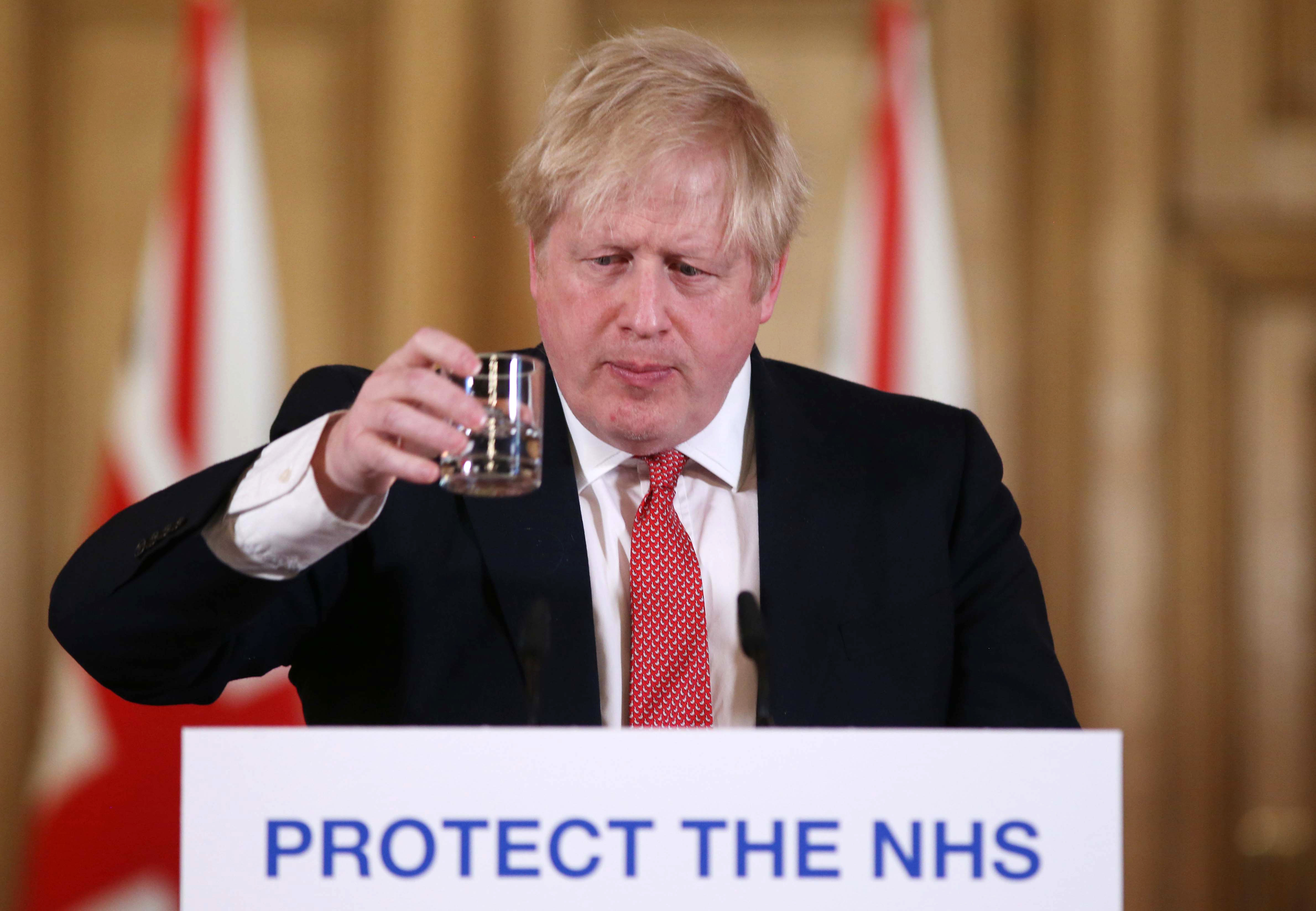 Britain's Prime Minister Boris Johnson takes a drink of water during a news conference to give a daily update on the government's response to the novel coronavirus COVID-19 outbreak, inside 10 Downing Street in London on March 22, 2020. (IAN VOGLER/POOL/AFP via Getty Images)