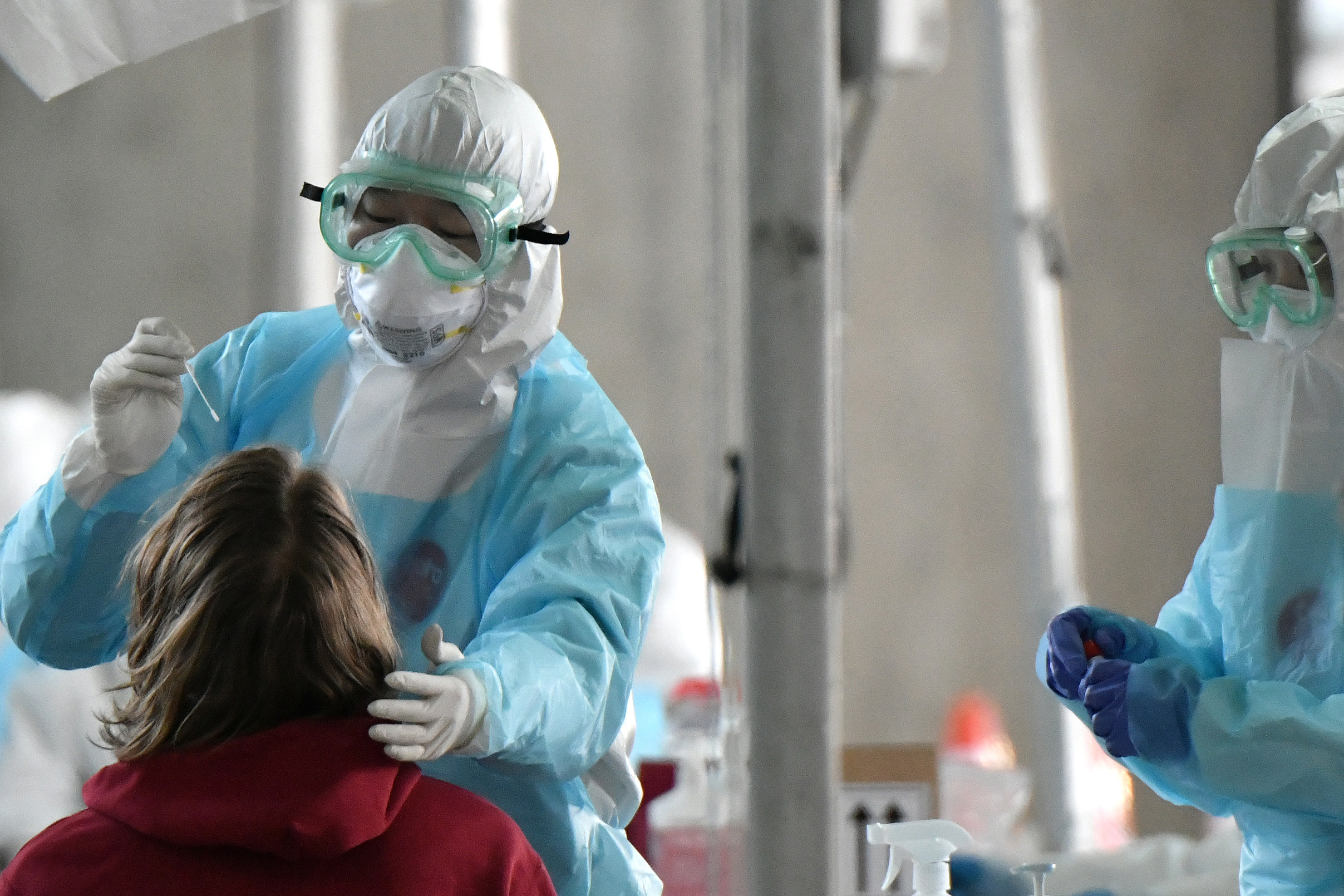 A medical staff wearing protective clothing takes test samples for the COVID-19 coronavirus from a foreign passenger at a virus testing booth outside Incheon international airport, west of Seoul, on April 1, 2020. (JUNG YEON-JE/AFP via Getty Images)