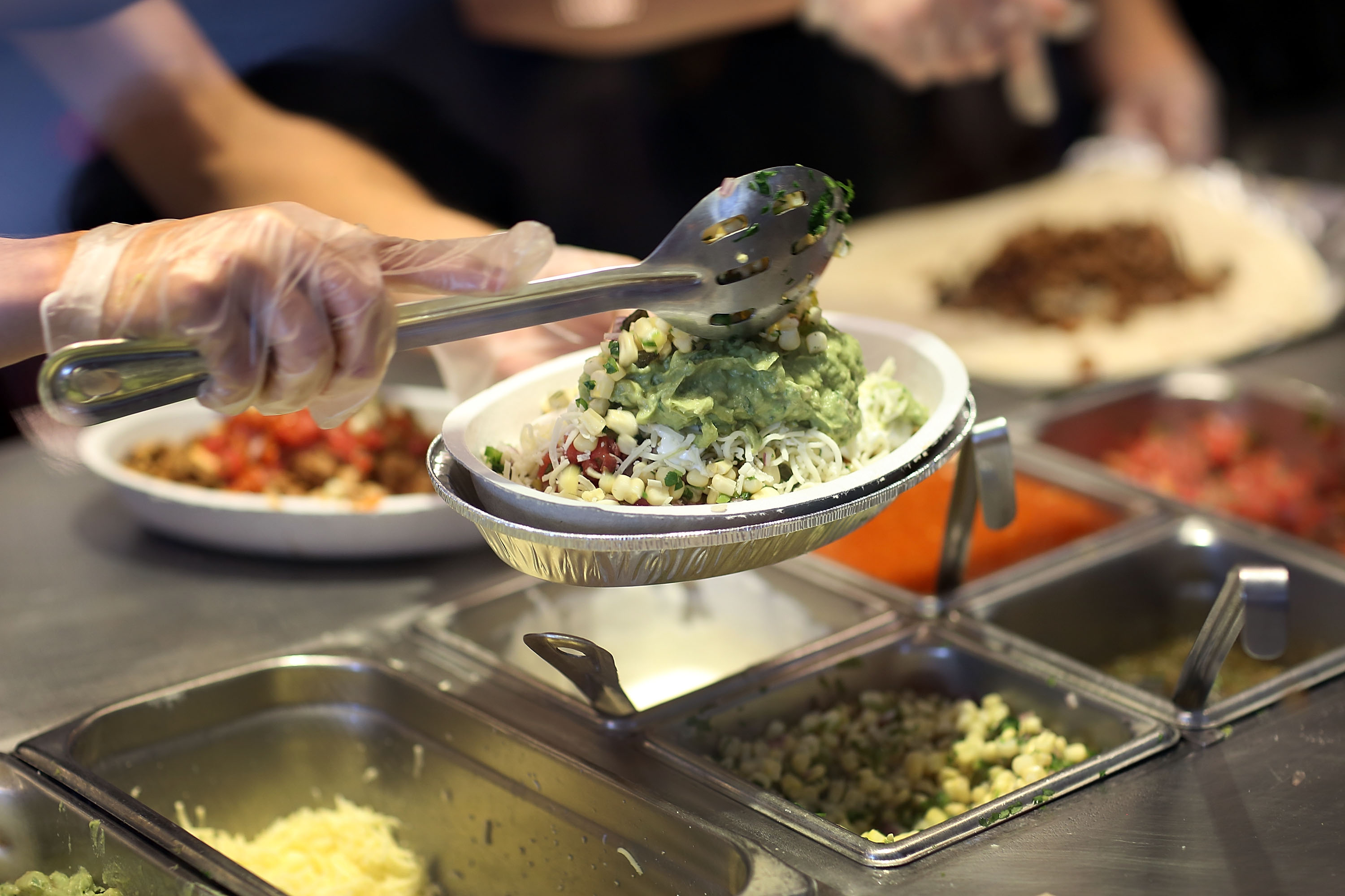 Chipotle restaurant workers fill orders for customers on the day that the company announced it will only use non-GMO ingredients in its food on April 27, 2015 in Miami, Florida. (Photo by Joe Raedle/Getty Images)