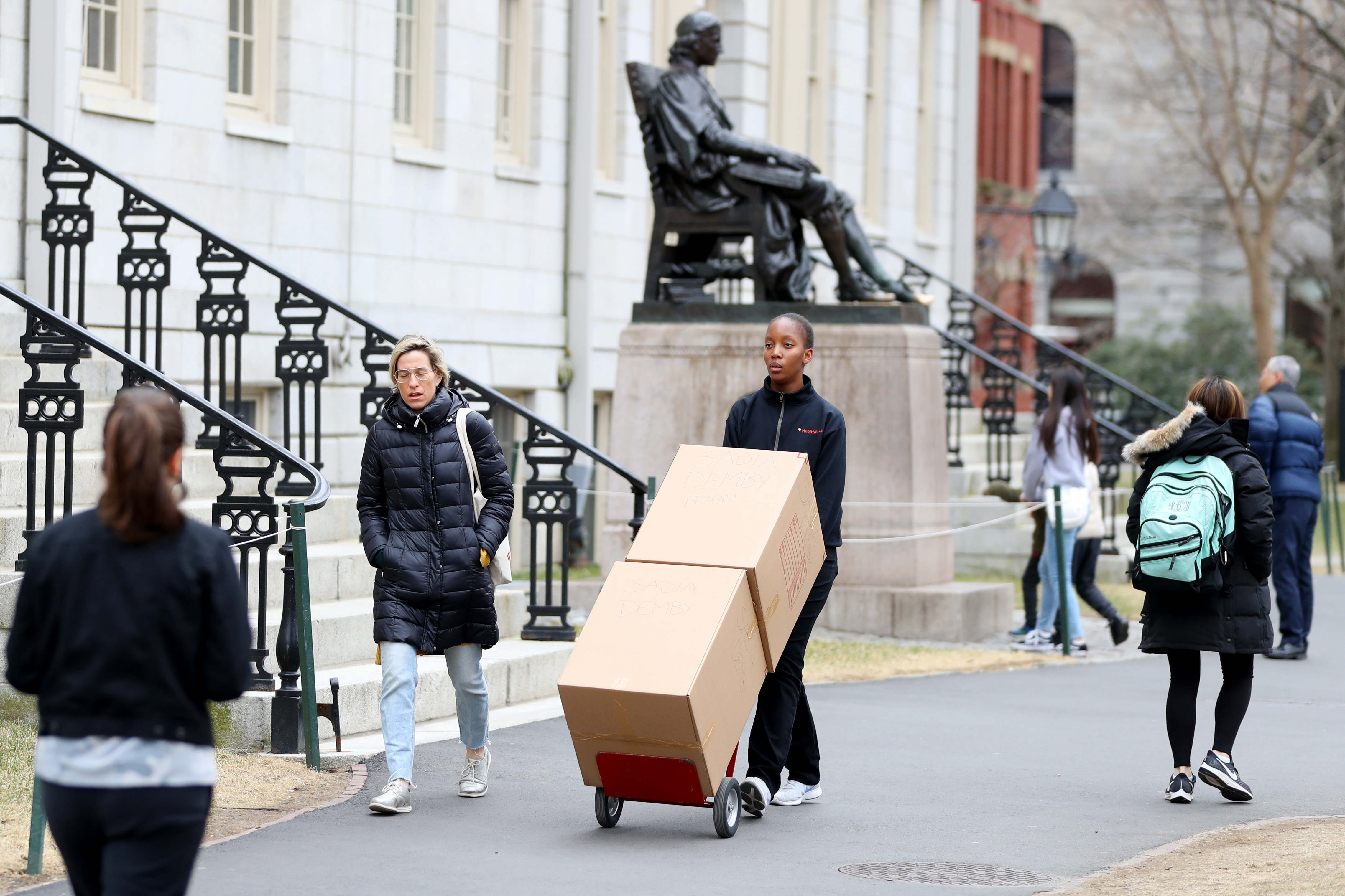 CAMBRIDGE, MASSACHUSETTS - MARCH 12: Sophomore Sadia Demby moves her belongings through Harvard Yard on the campus of Harvard University on March 12, 2020 in Cambridge, Massachusetts. Students have been asked to move out of their dorms by March 15 due to the Coronavirus (COVID-19) risk. All classes will be moved online for the rest of the spring semester. (Photo by Maddie Meyer/Getty Images)