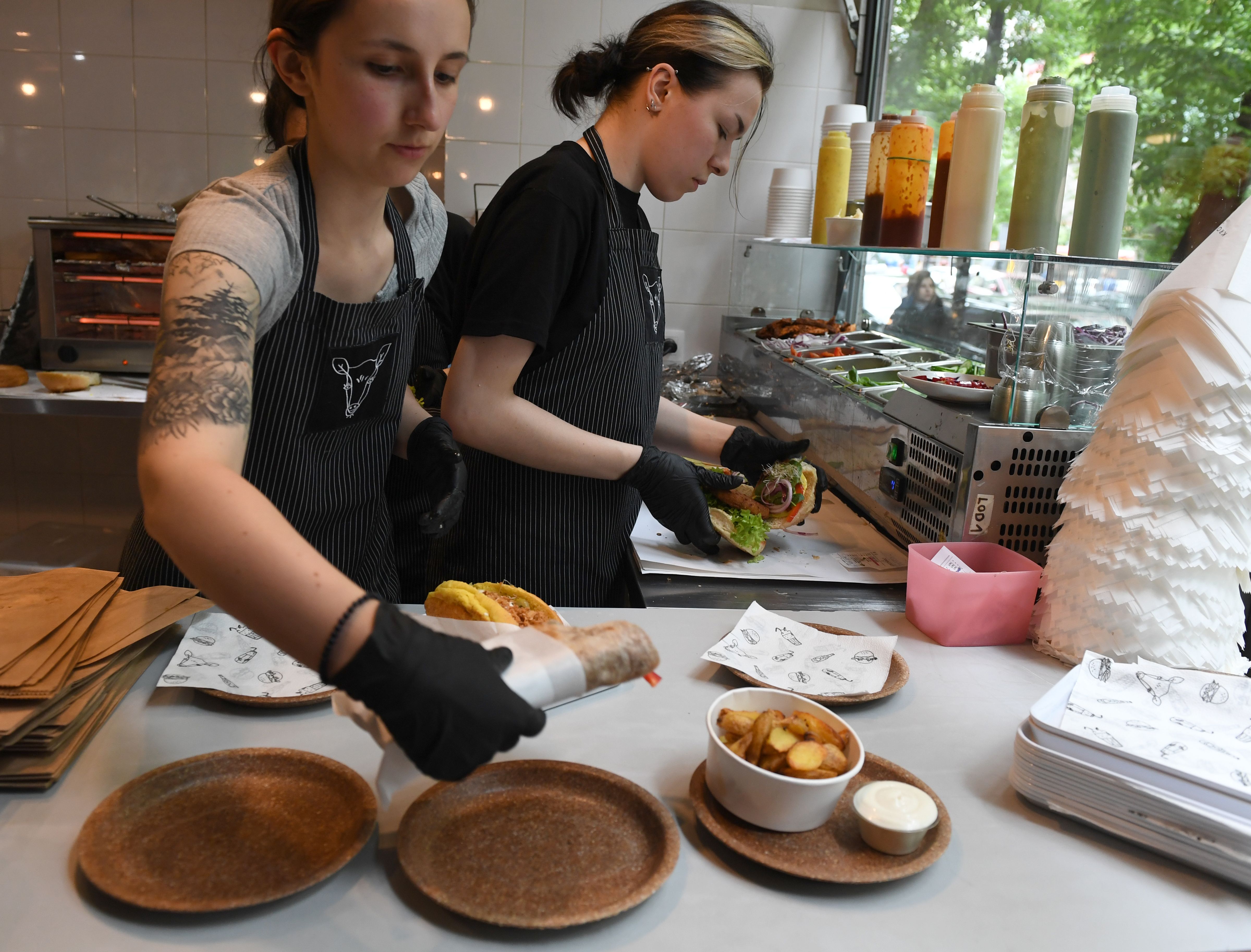 Women working in one of Warsaw's vegan restaurants serve meals on wheat bran plates produced at the Biotrem factory in Zambrow, Poland, on May 29, 2019. - (JANEK SKARZYNSKI/AFP via Getty Images)