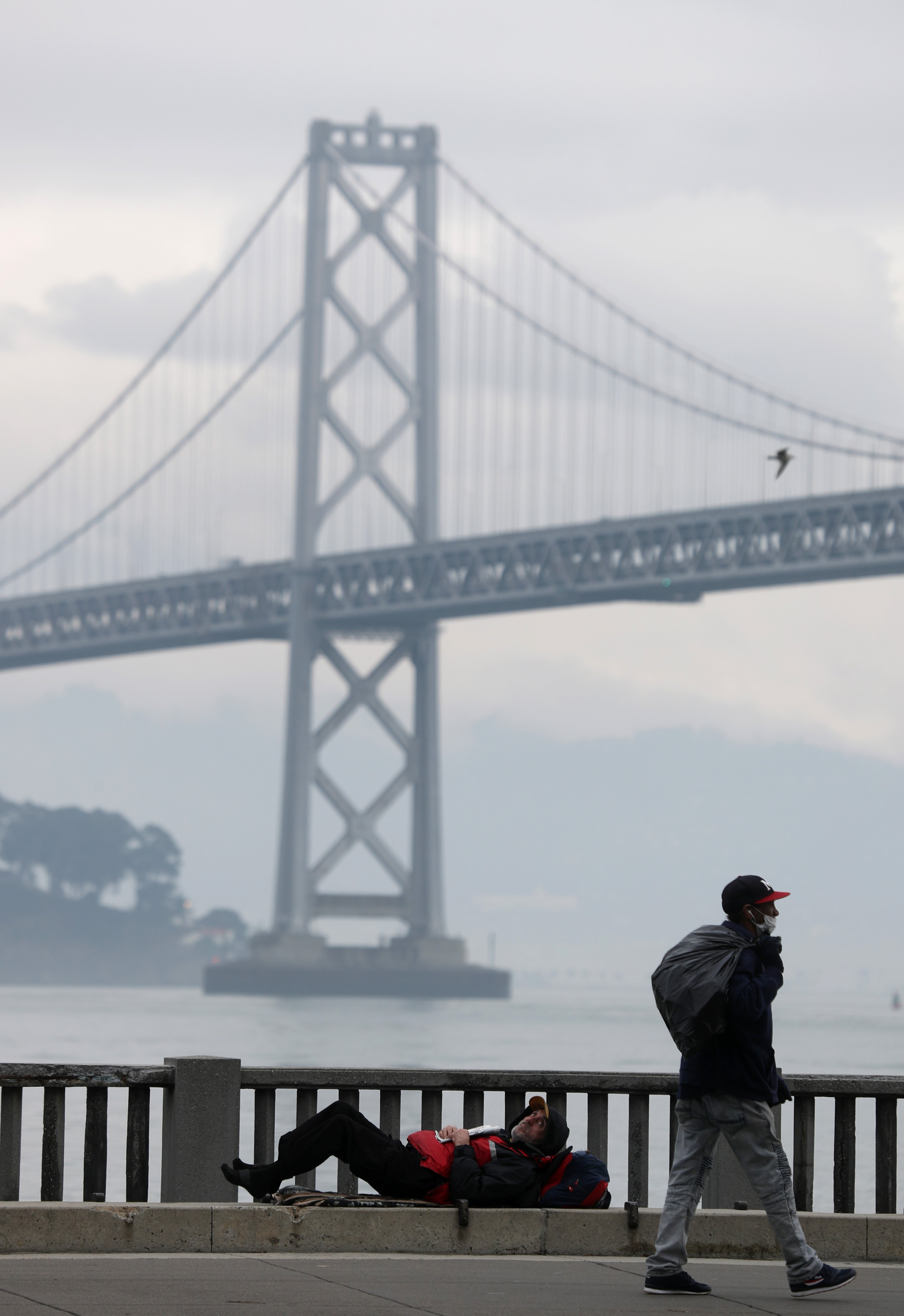 A homeless man lays on the sidewalk near the San Francisco–Oakland Bay Bridge on December 05, 2019 in San Francisco, California. (Photo by Justin Sullivan/Getty Images)