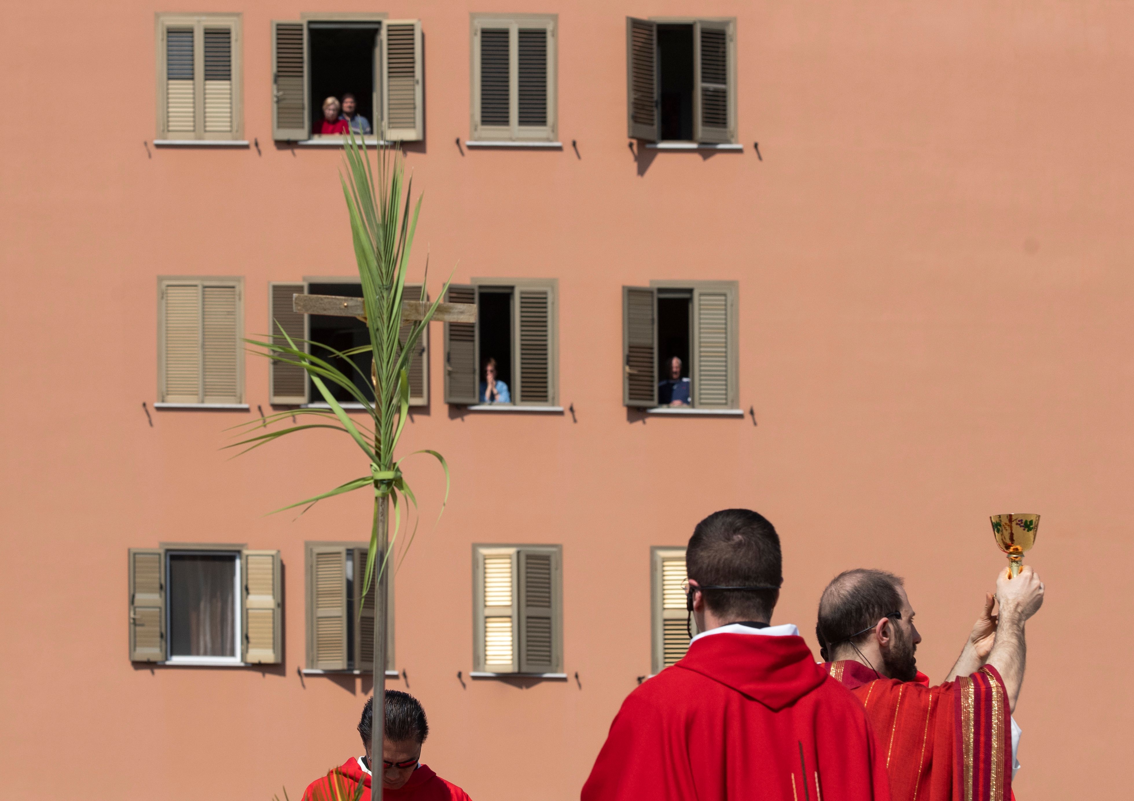 Parish priest Don Antonio Lauri (R) holds the Chalice as he celebrates Palm Sunday mass for nearby residents from the rooftop of the San Gabriele dell'Addolorata church in Rome on April 5, 2020, during the country's lockdown. (Photo by TIZIANA FABI/AFP via Getty Images)