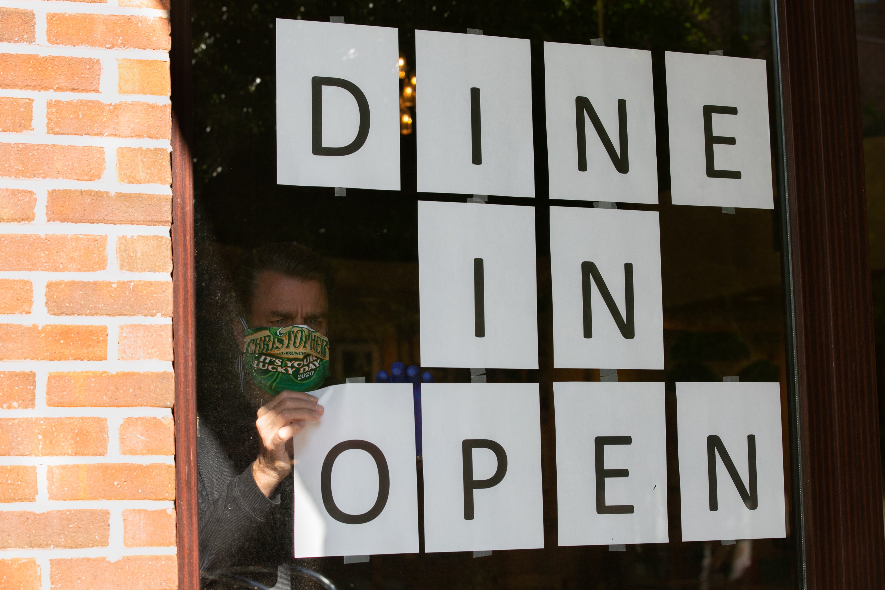 Barry Lennon, Operating Partner of J. Christopher, hangs up signs to to promote dine in service now available in the J. Christopher restaurant on April 27, 2020 in Brookhaven, Georgia. (Photo by Jessica McGowan/Getty Images)