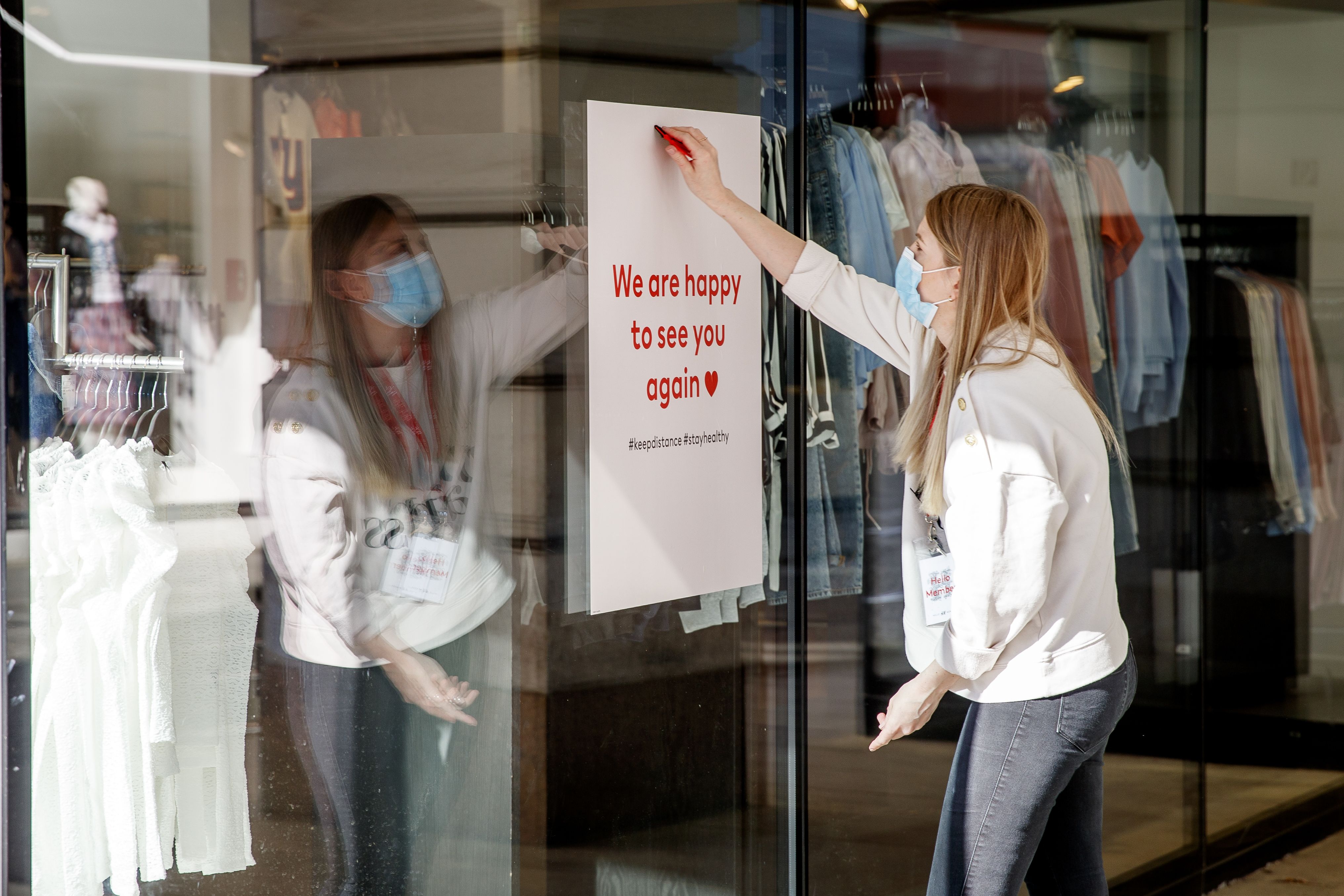 An employee fixes a placard reading 'We are happy to see you again' on a shop window in Graz, Austria on May 2, 2020, after authorities eased down some of the measures. (Photo by ERWIN SCHERIAU/APA/AFP via Getty Images)
