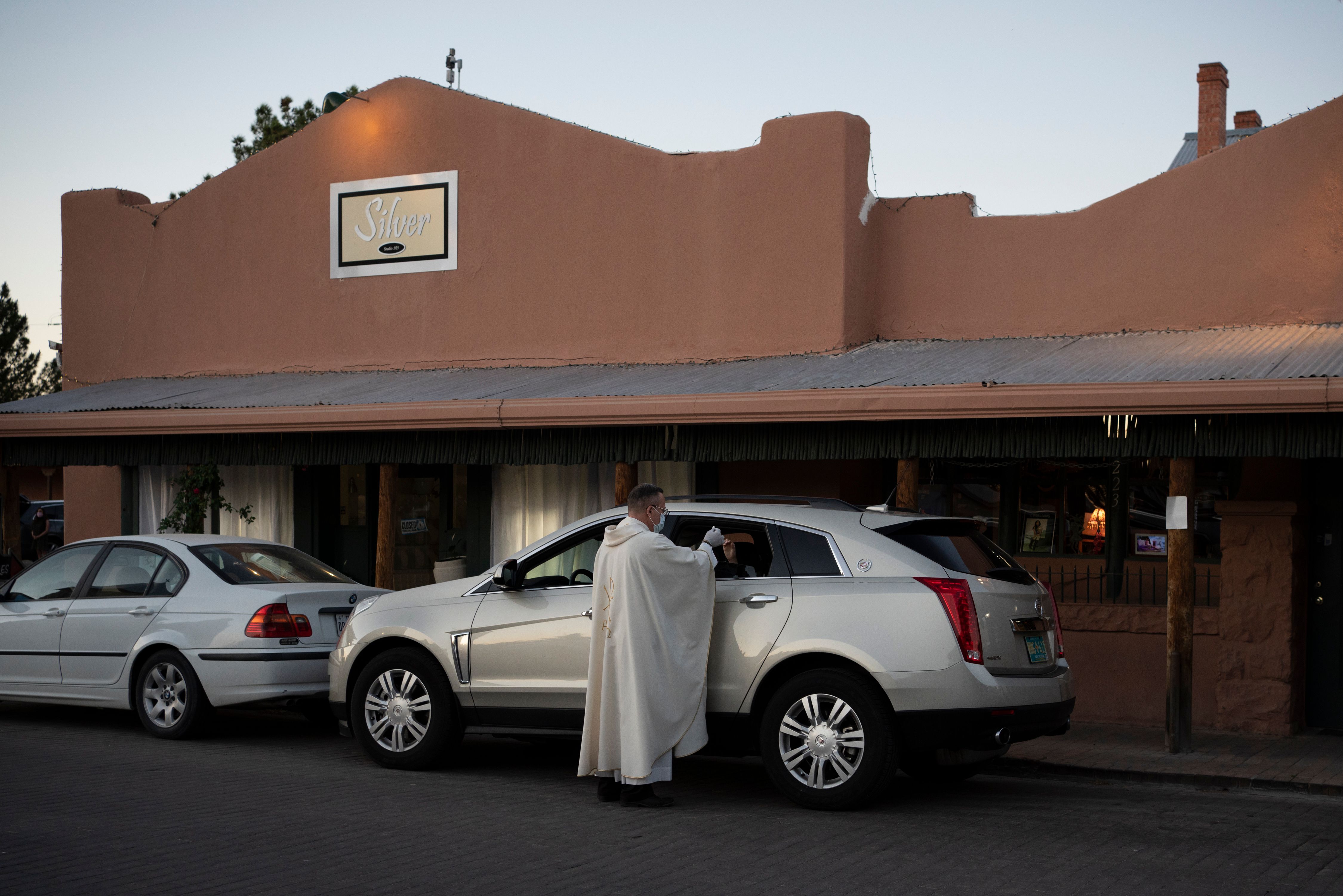 Father Christoper Williams gives communion to parishioners in their cars outside of the Basilica of San Albino on May 2, 2020. (Photo by PAUL RATJE/AFP via Getty Images)