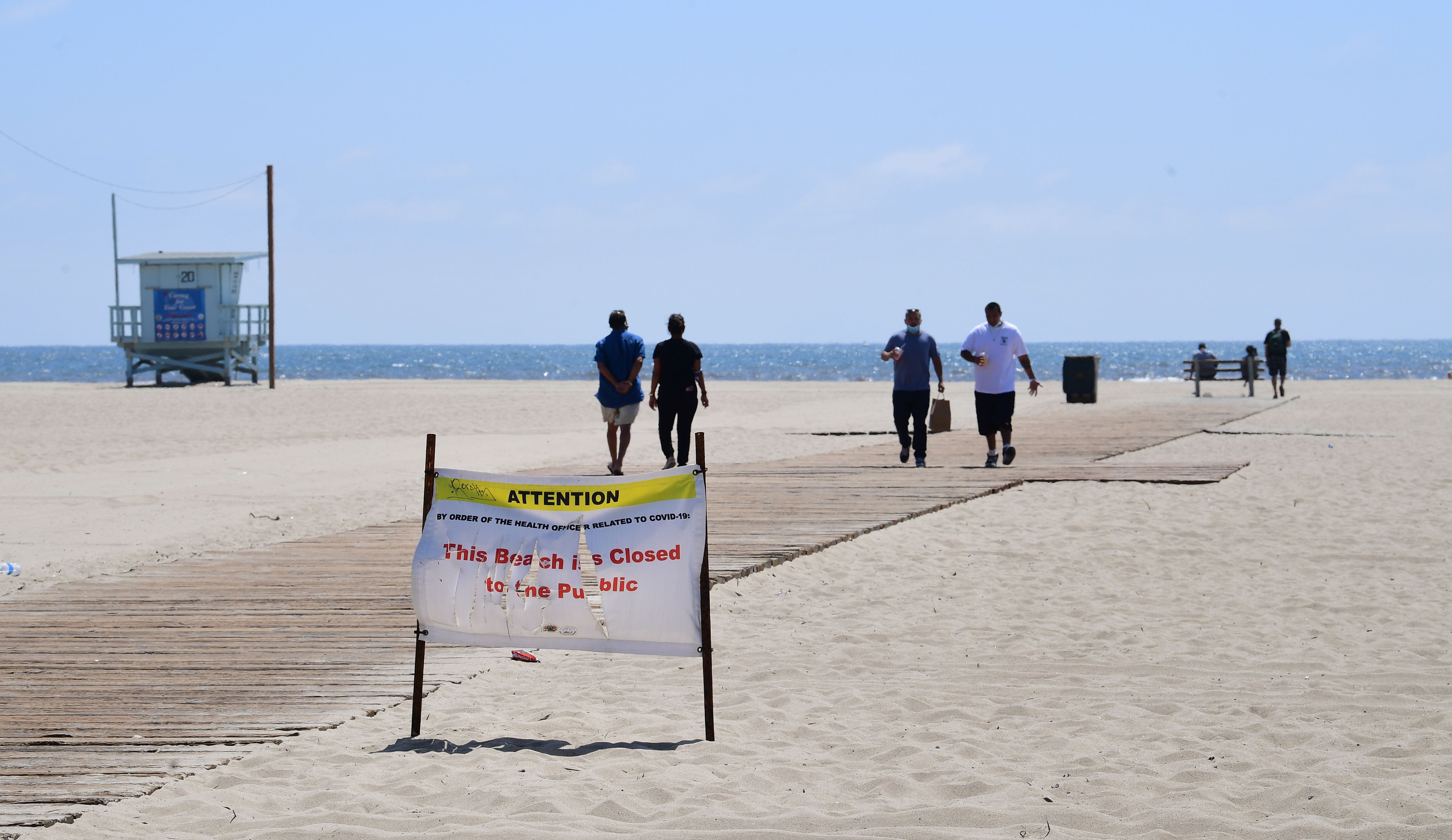 People visit Santa Monica Beach in Santa Monica, California on May 11, 2020, despite a sign mentioning beach closure due to the coronavirus pandemic.(Photo by FREDERIC J. BROWN/AFP via Getty Images)