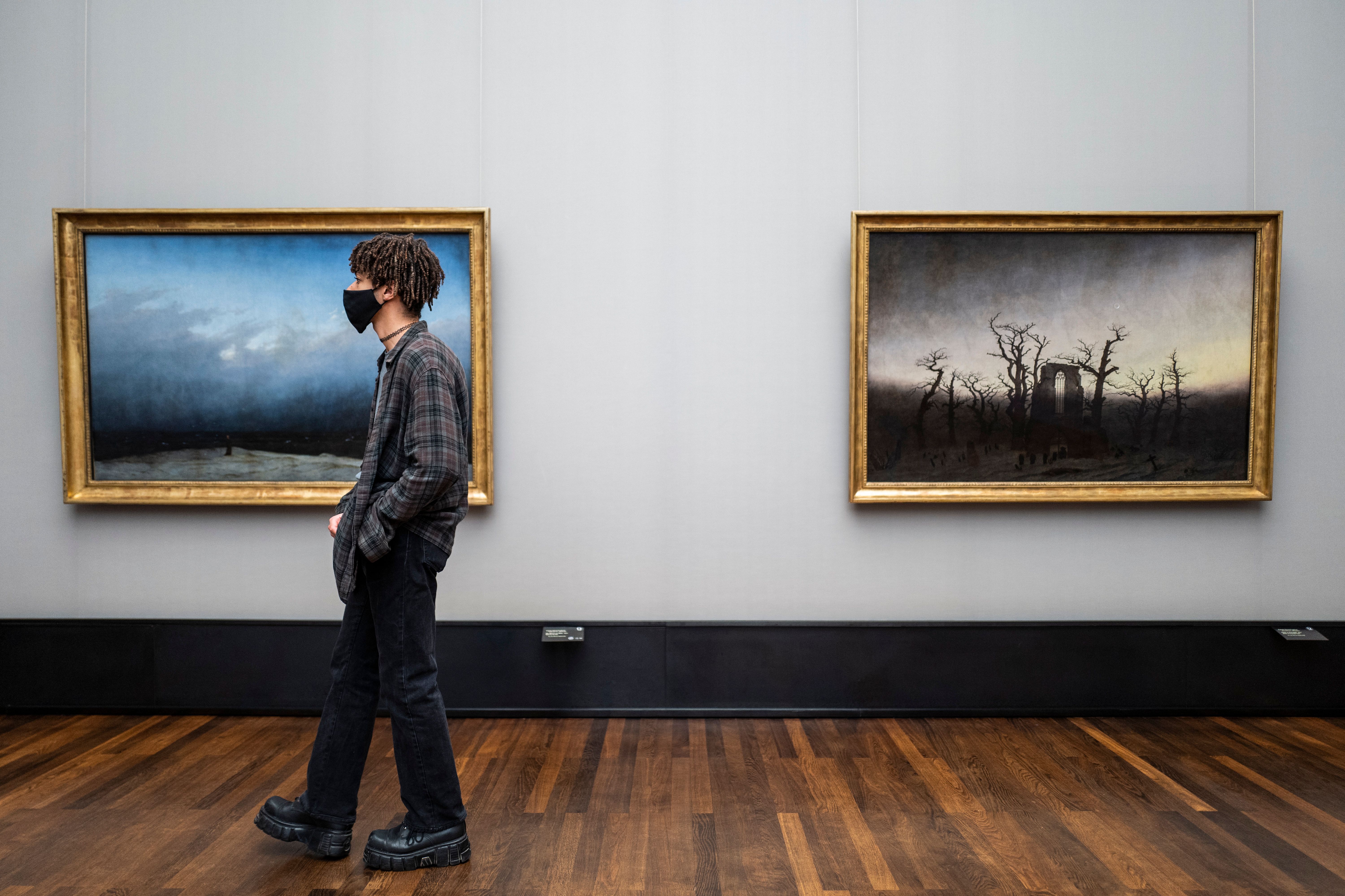 A visitor wearing a face mask walks past two paintings by Caspar David Friedrich at the Alte Nationalgalerie (Old National Gallery) museum in Berlin on May 12, 2020. (Photo by JOHN MACDOUGALL/AFP via Getty Images)