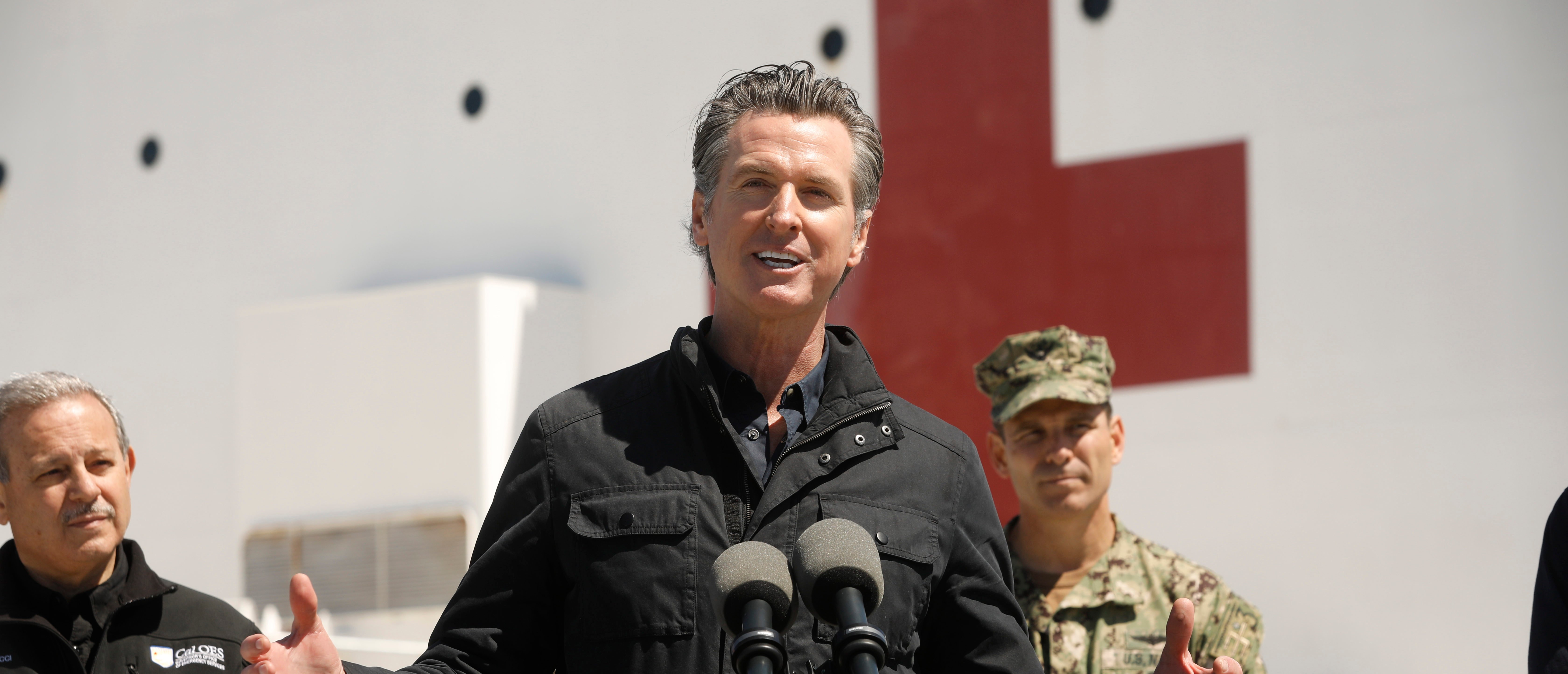 LOS ANGELES, CA - MARCH 27: California Governor Gavin Newsom speaks in front of the hospital ship USNS Mercy that arrived into the Port of Los Angeles on Friday, March 27, 2020, to provide relief for Southland hospitals overwhelmed by the coronavirus pandemic. Also attending the press conference were Director Mark Ghilarducci, Cal OES, left, Admiral John Gumbleton, United States Navy, right, and many others not shown including Mayor Eric Garcetti and Dr. Mark Ghaly, Secretary of Health and Human Services. (Photo by Carolyn Cole-Pool/Getty Images)